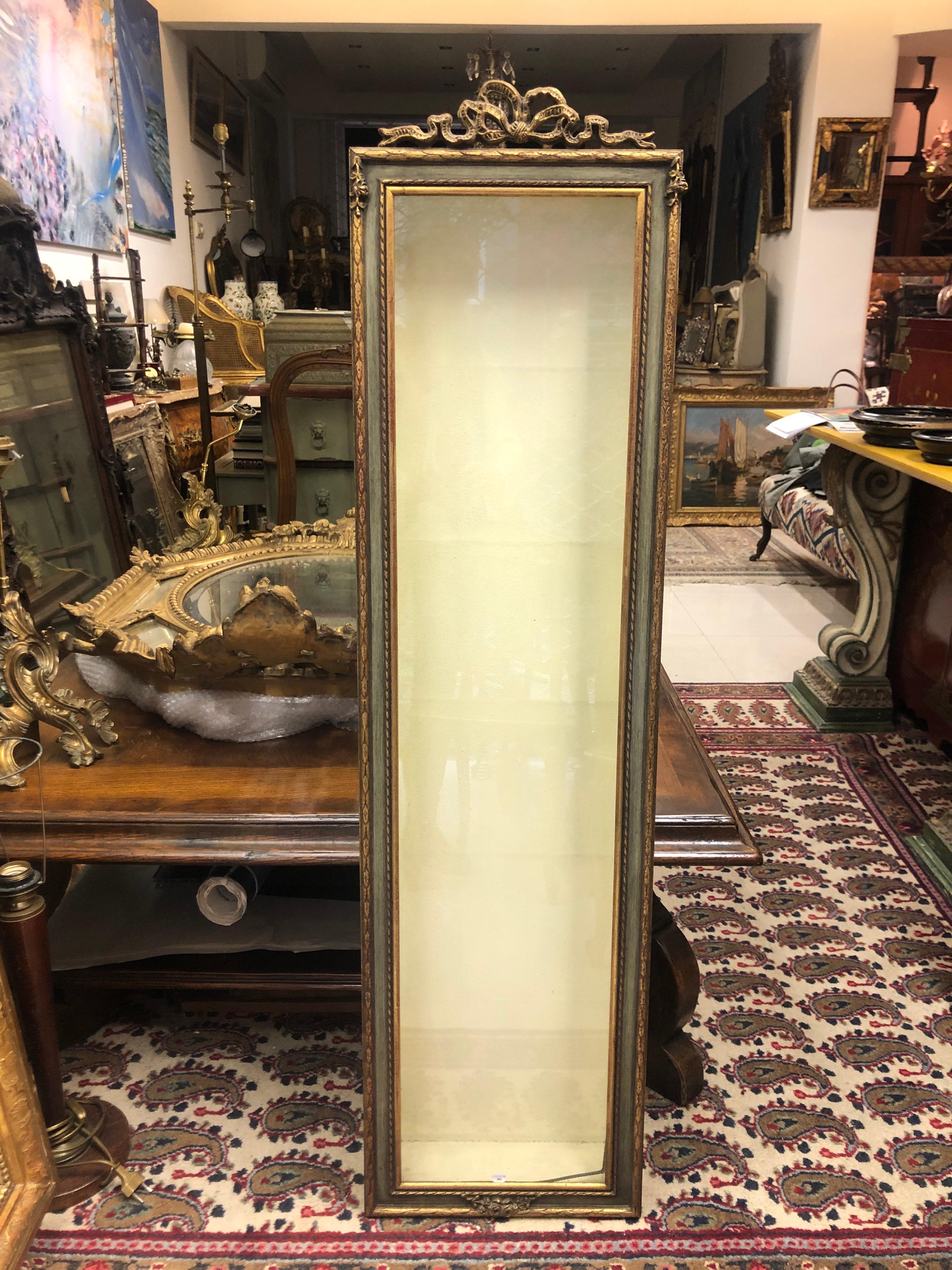 Vintage wooden hand painted wall mounted vitrine with typical Louis XVI decoration, that opens with glass door and contains four glass shelves.
France, circa 1950.
