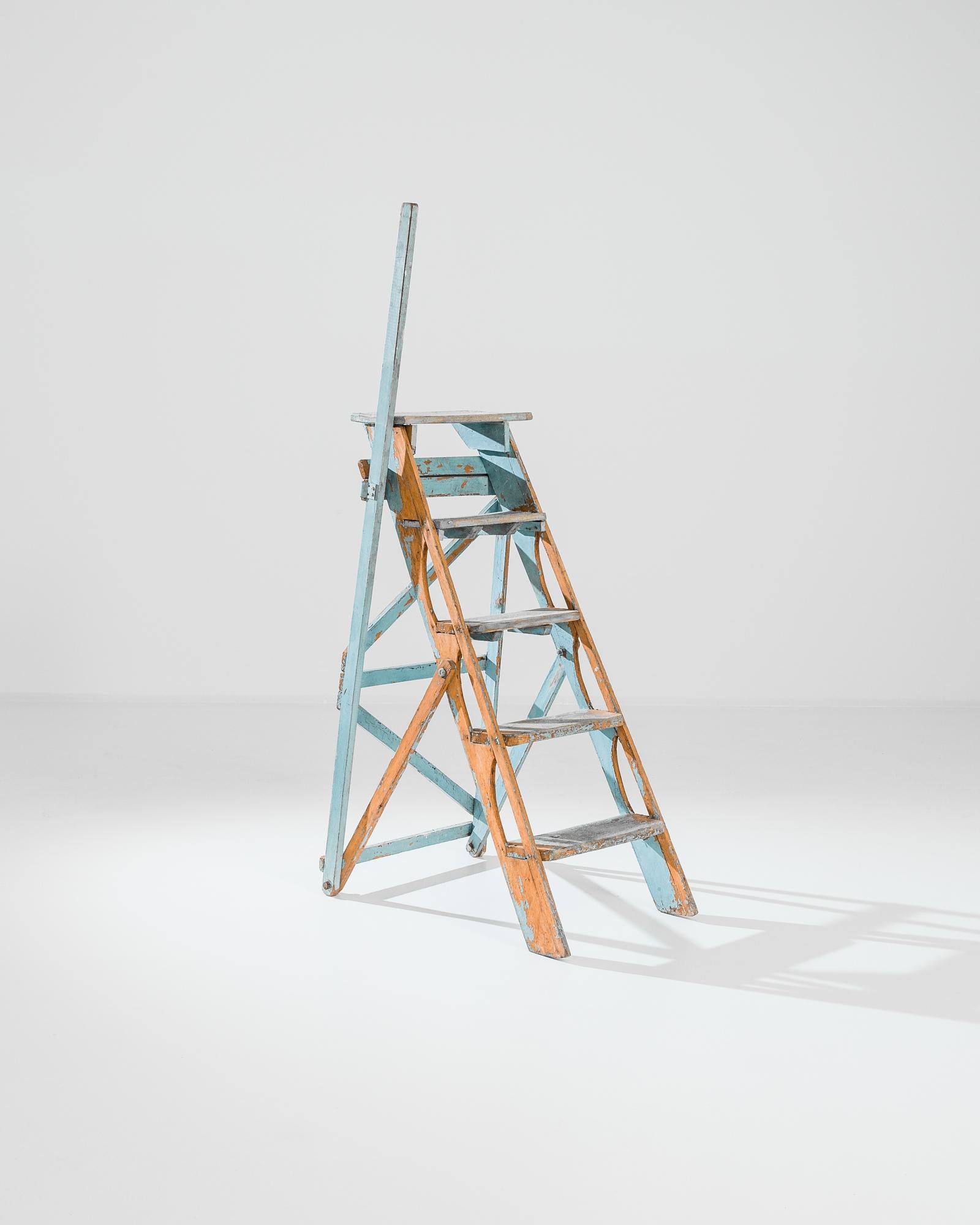 Nearly five feet tall, this folding wooden ladder was made in France, circa 1900. Optimistic light blue and orange colors of the original finish lend a cheerful touch, while practical elements also make playful decorations: cross braces and carved