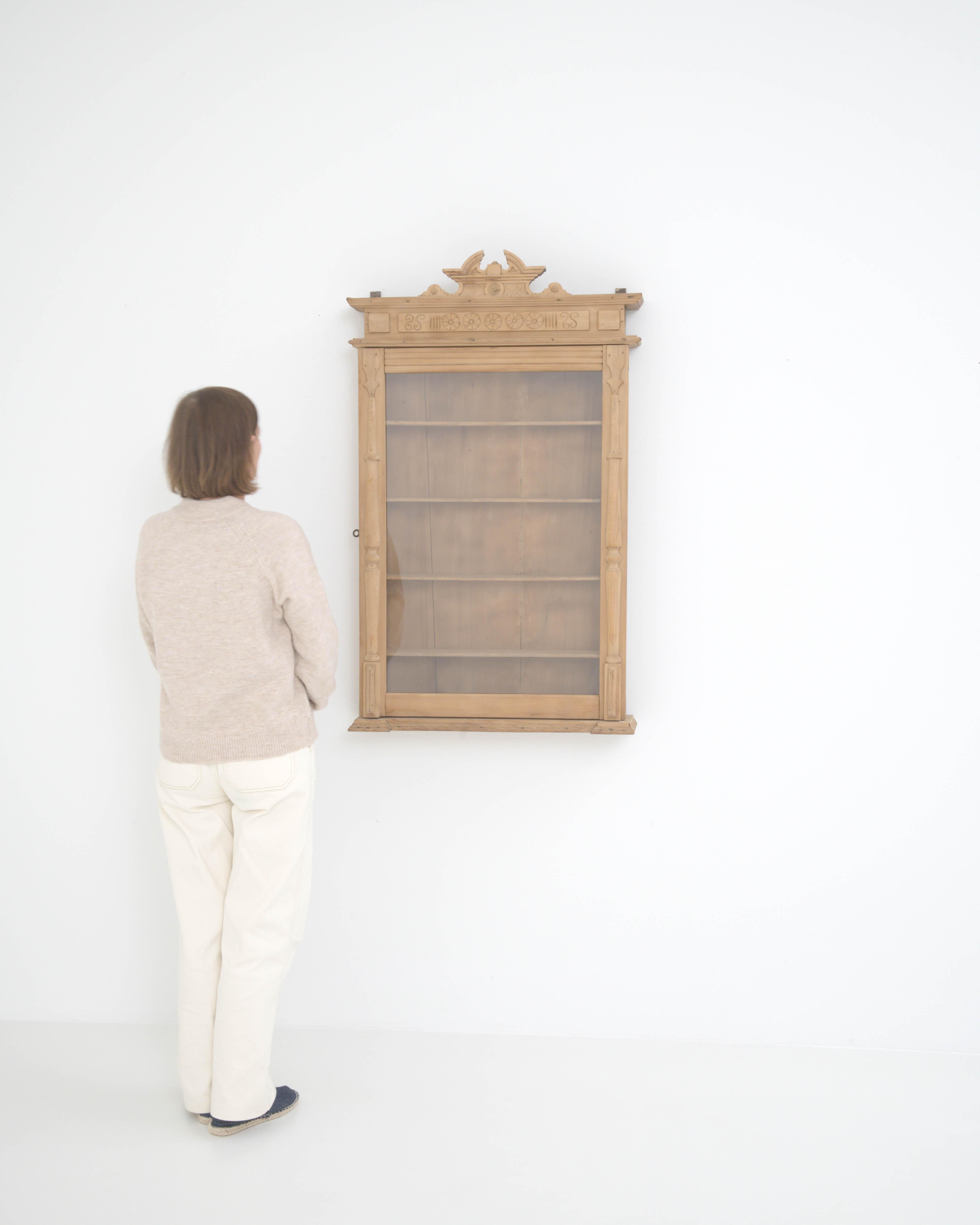 Radiating the distinctive charm of French country furniture, this slender wall vitrine was made in France circa 1900. Its carved wooden ornament draws attention, and announces this piece’s purpose: both to protect and display its contents. The