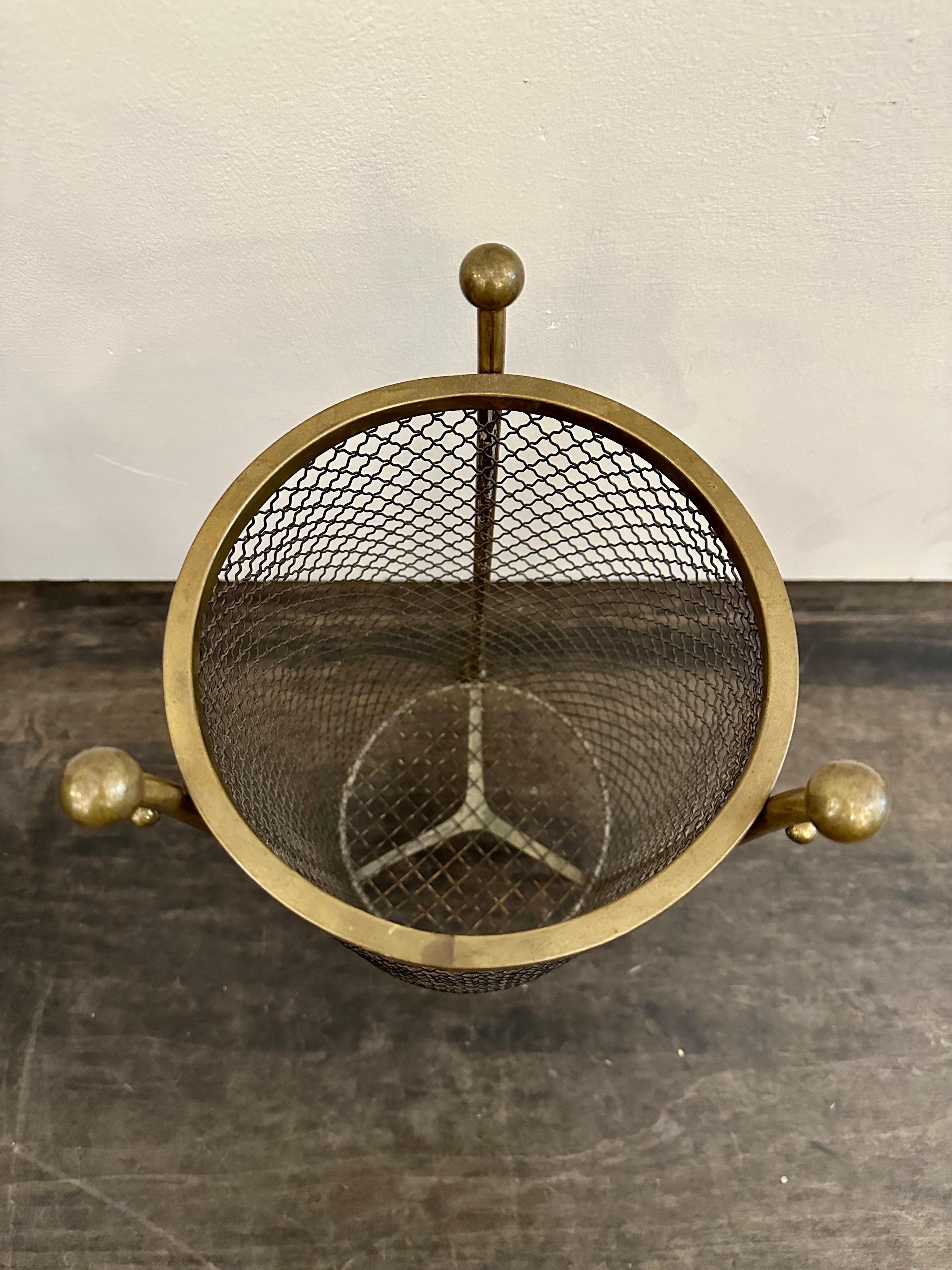 This lovely vintage metal mesh and brass waste basket is VERY utilitarian.  1960's and beautiful scale for an office, powder room, etc. in the style of Jean Royere.  THIS ITEM IS LOCATED AND WILL SHIP FROM OUR EAST HAMPTON, NY SHOWROOM.
