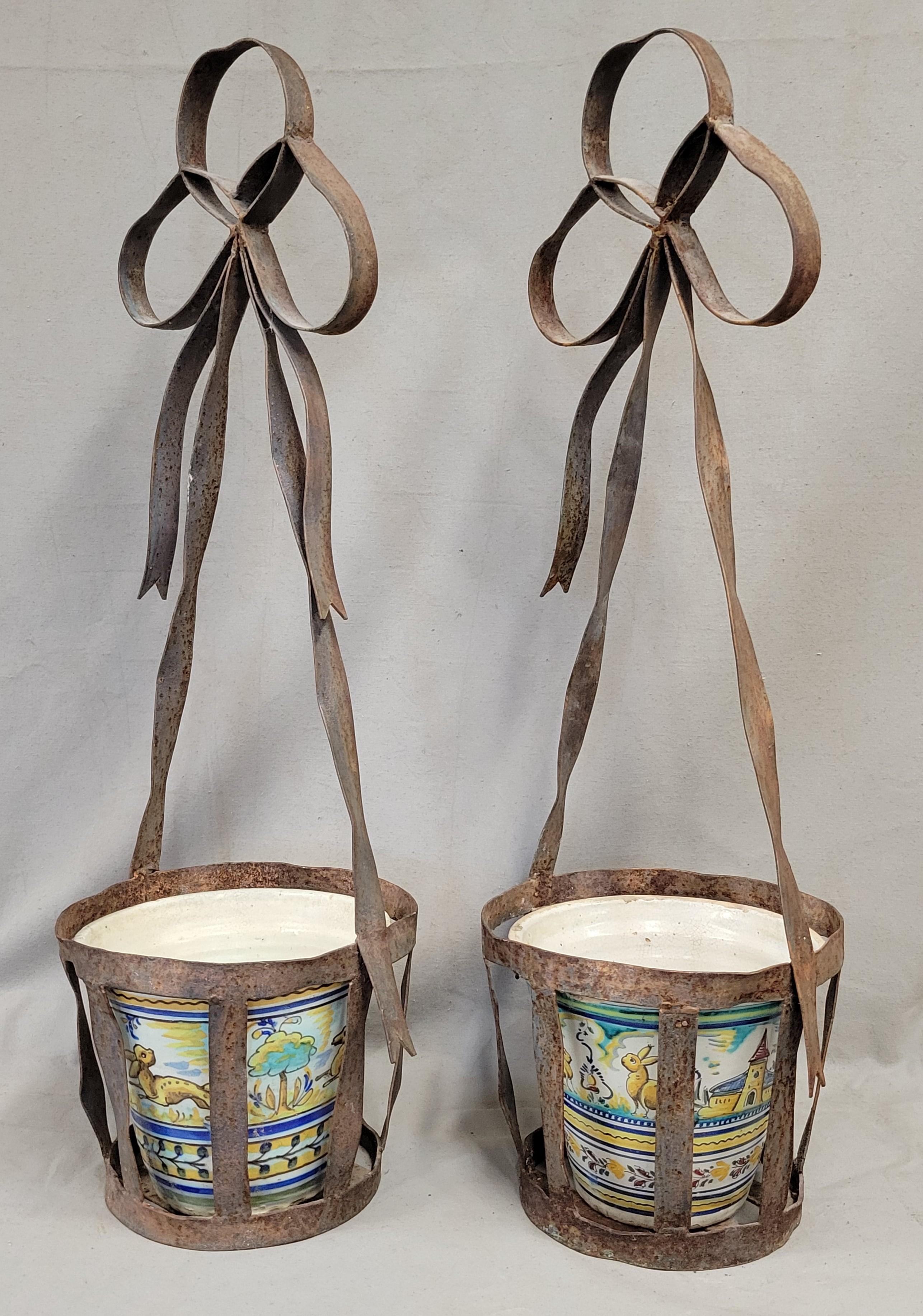 A charming pair of vintage French planters comprised of wrought iron and Spanish ceramic pots. These planters could be hung from hooks or placed on the ground or a table top. Collected in France. 
Iron 