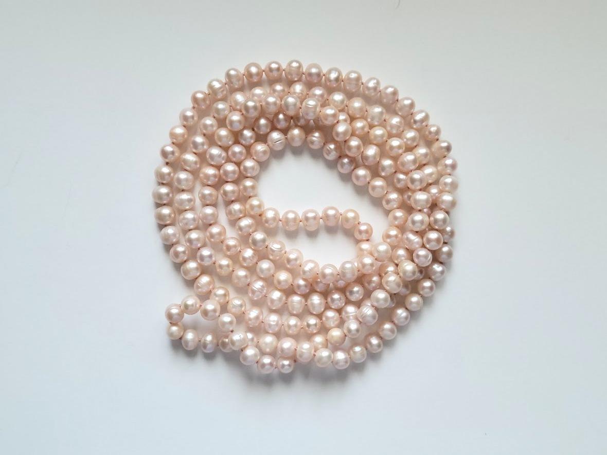 This is a cream-pink natural freshwater pearl necklace that is long at approximately 64″ from end to end – long, beautiful, and elegant.
There is no clasp on this necklace as it is one extra long continual strand, or you can wear it with multiple
