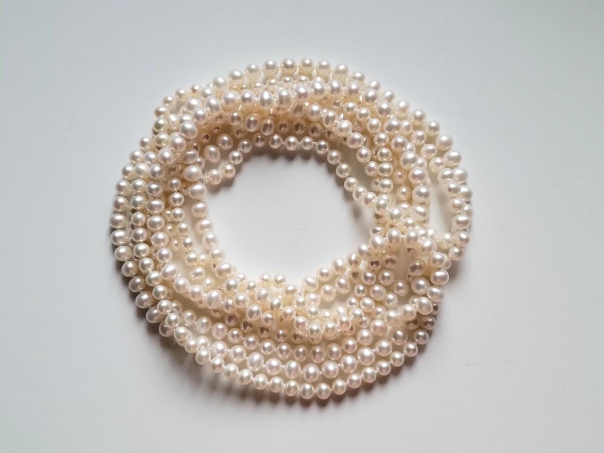 This is a white natural freshwater pearl necklace that is very long at approximately 102″ from end to end – long, beautiful, and elegant.
There is no clasp on this necklace as it is one extra long continual strand, or you can wear it with multiple