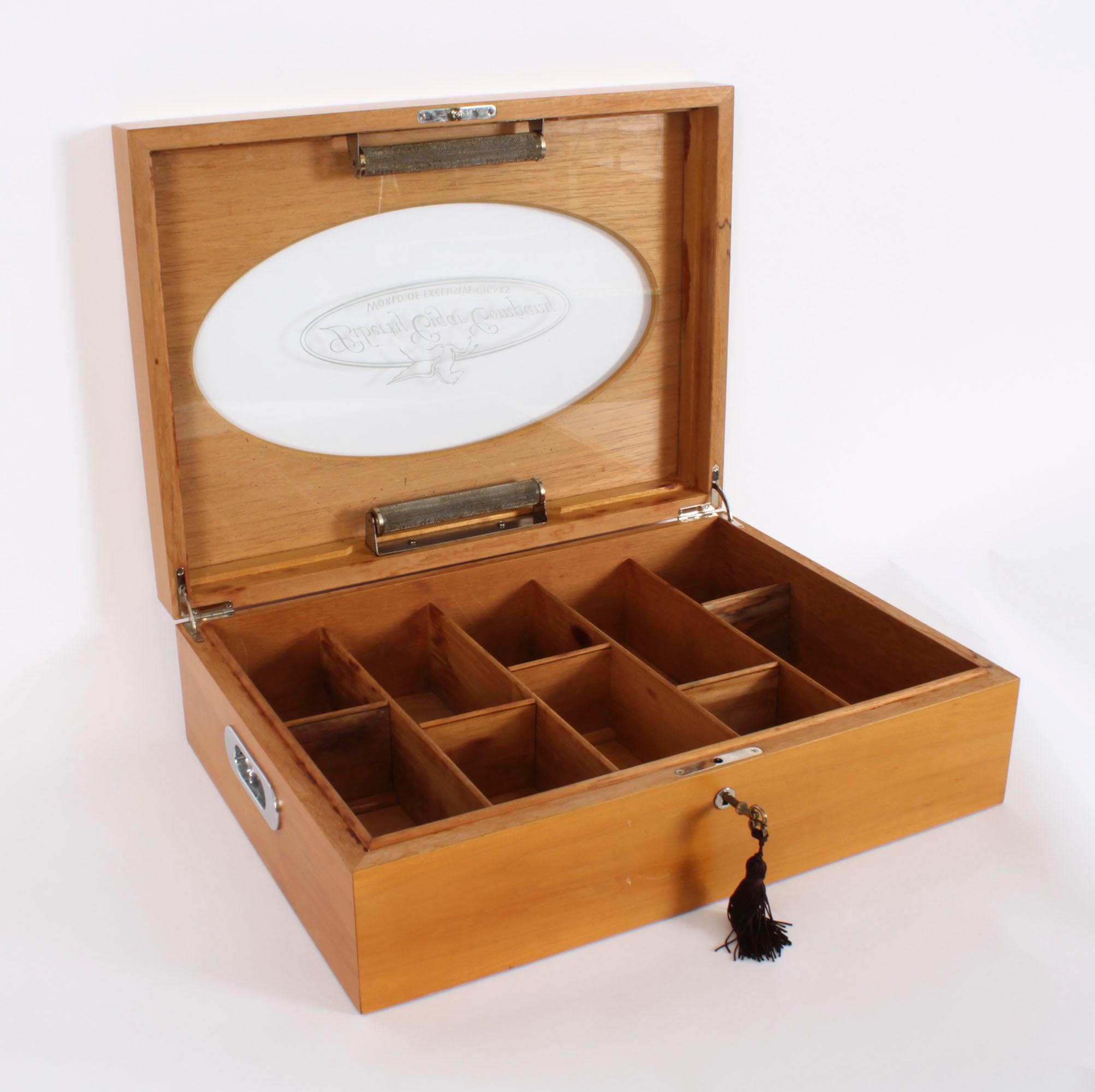 An elegant Vintage English  fruitwood humidor with fitted interior, mid 20th century in date.

The rectangular humidor features a hinged lid having an oval cut out with a glass viewing panel that bears the logo for the 