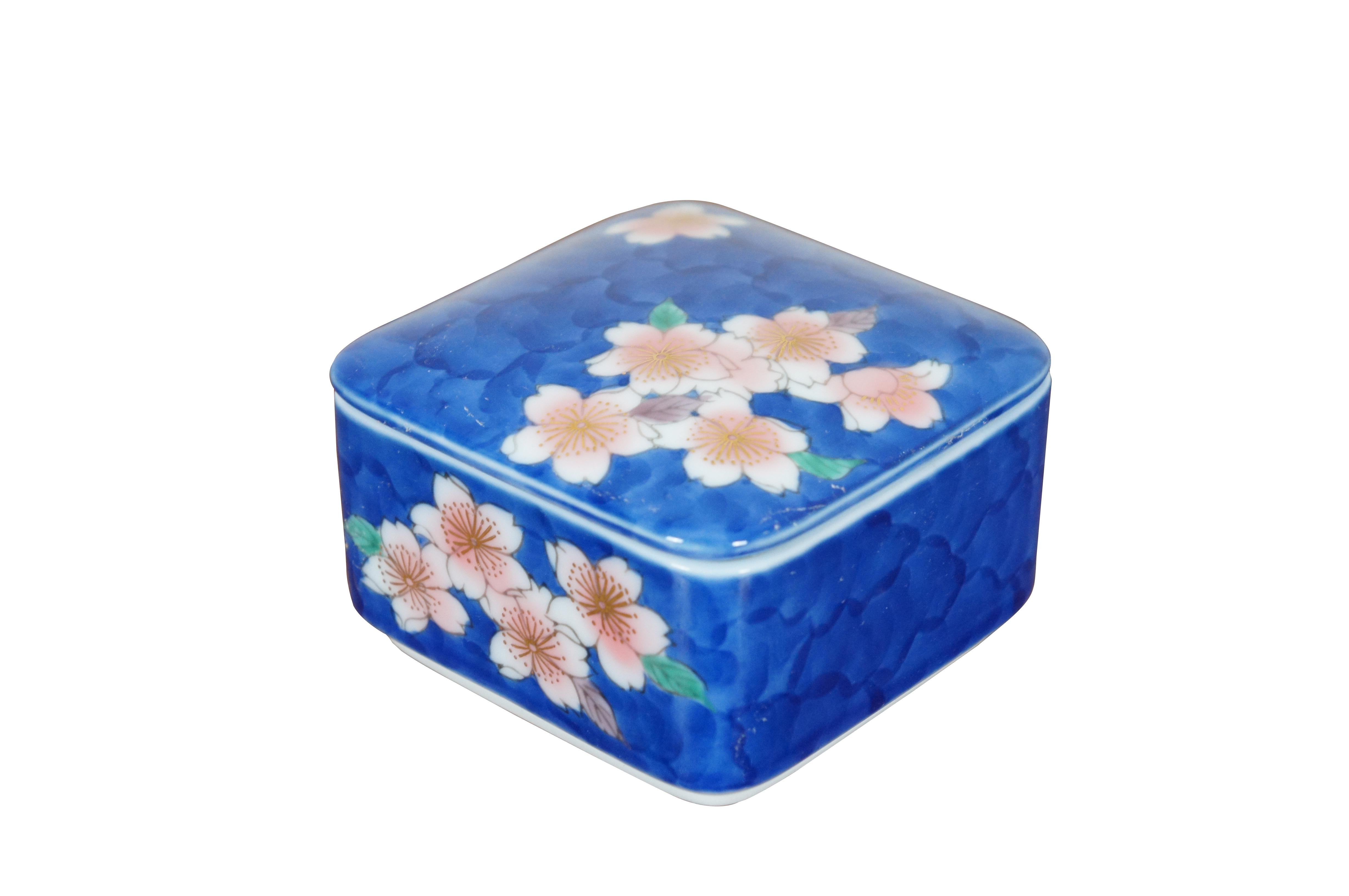 Vintage hand painted porcelain trinket box. Rounded square form with pink water lilies / lotus flowers accented with gold stamens and green leaves on a backdrop of blue water. Mark used circa 1900-1920.

