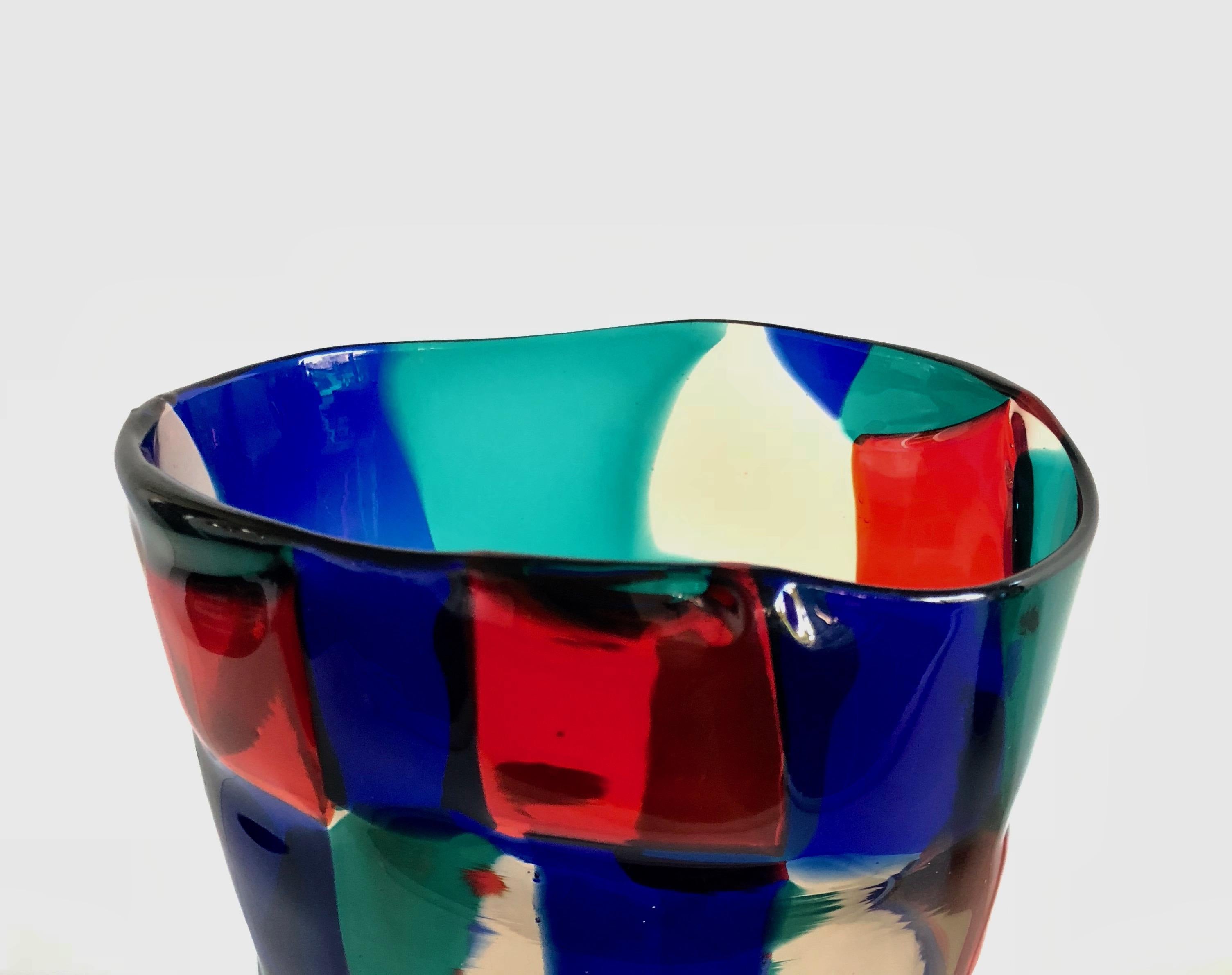 A vintage Venini vase designed by Fulvio Bianconi for Venini.
Known as model 4910.
Transparent straw colored, red, sapphire and green patches of glass.
This piece which has a slightly flared body has an oval cross section.
Designed between