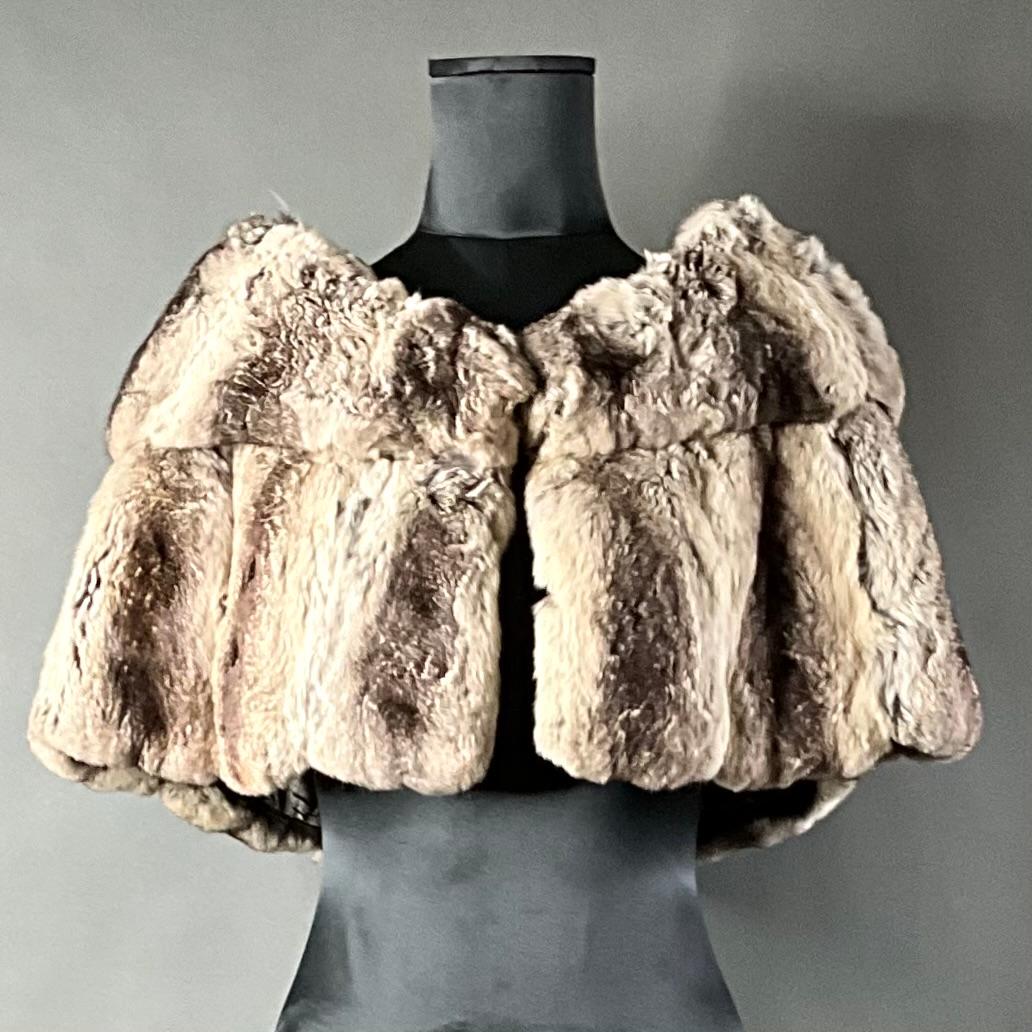 Lo scialle in pelliccia di coniglio Vintage Furs by Mr. Herman è un pezzo lussuoso e senza tempo che unisce eleganza e calore pratico. Realizzato con una pregiata pelliccia di coniglio, questo cappotto offre una sensazione di morbidezza e peluche e