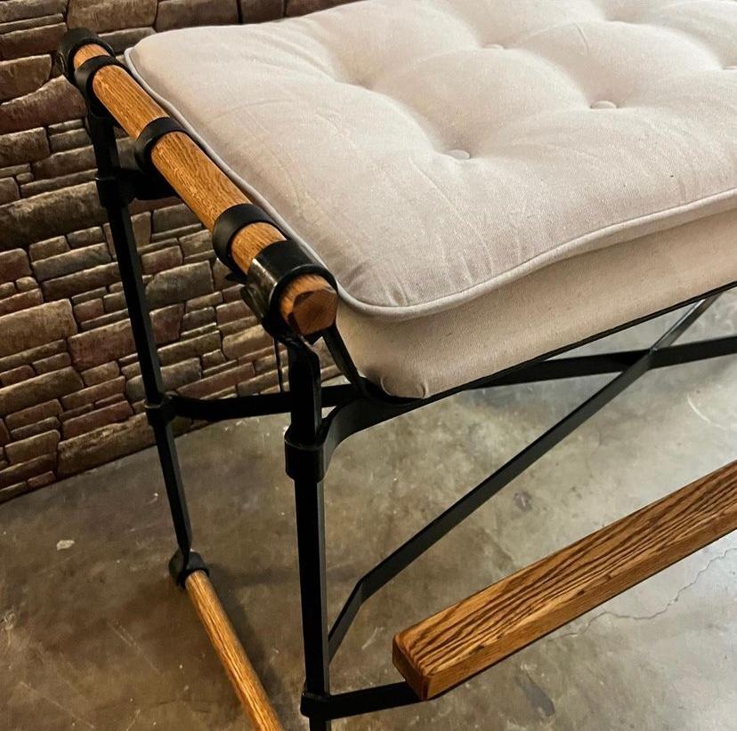 Vintage gallery bench by Cleo Baldon for Terra Furniture features a wrought iron frame with oak dowels and oak foot rail. This bench is bar height and fully restored with canvas upholstery and tied / accented with black leather straps. 
Dimensions: