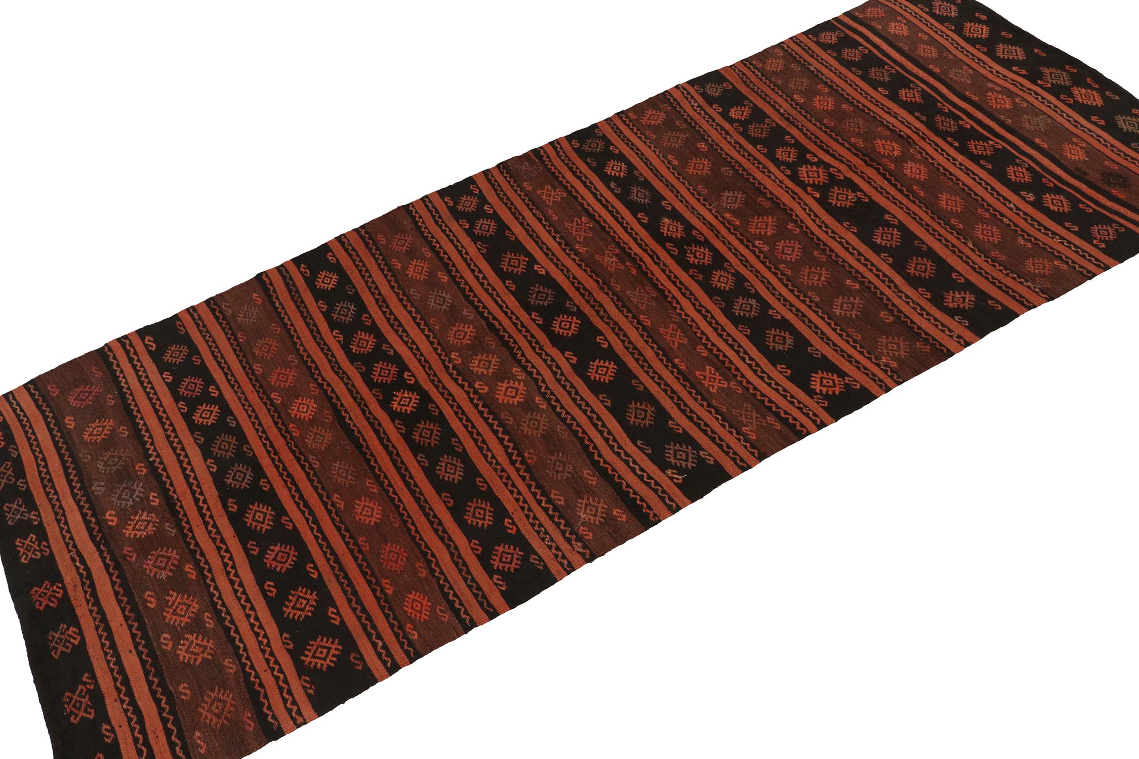 Procedente de Turquía, circa 1950-1960, un raro kilim vintage de tamaño galería, de una estética tribal inusual y ejemplar para su época. 

Tejida a mano en lana, la pieza luce dibujos bordados, motivos y rayas en ricos tonos marrones, negros y