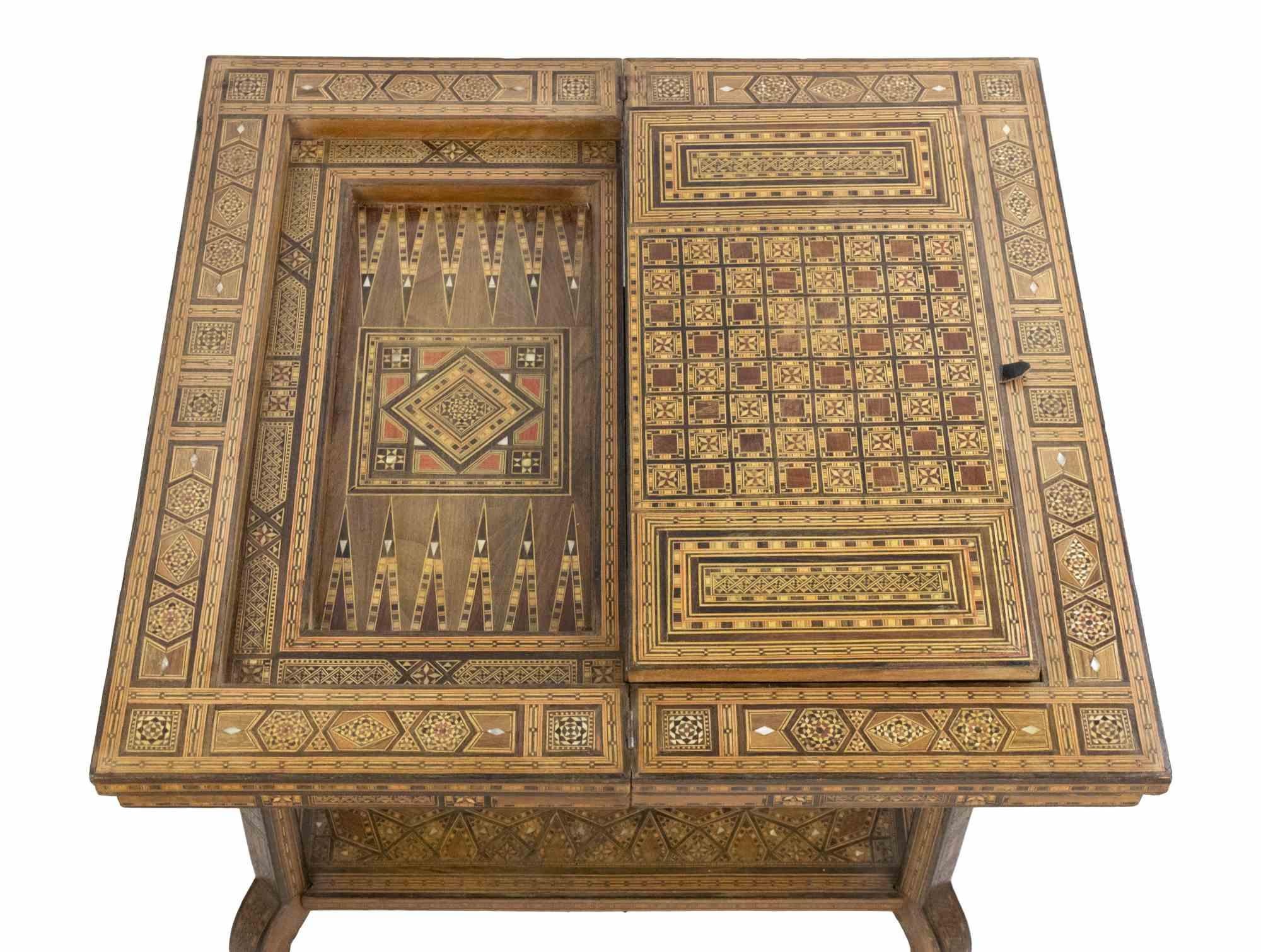 La mesa de juego vintage es un elemento de diseño realizado a principios del siglo XX.

Una mesa de diseño único finamente incrustada con motivos decorativos. 

Apertura superior (dimensiones: 61 x 61 cm)