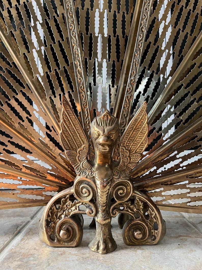 Add a touch of vintage elegance to your fireplace with this stunning Brass Peacock Fireplace Screen, likely crafted between the 1950s and 1970s. This beautifully designed piece features an intricate fan shape, unfolding gracefully to reveal detailed