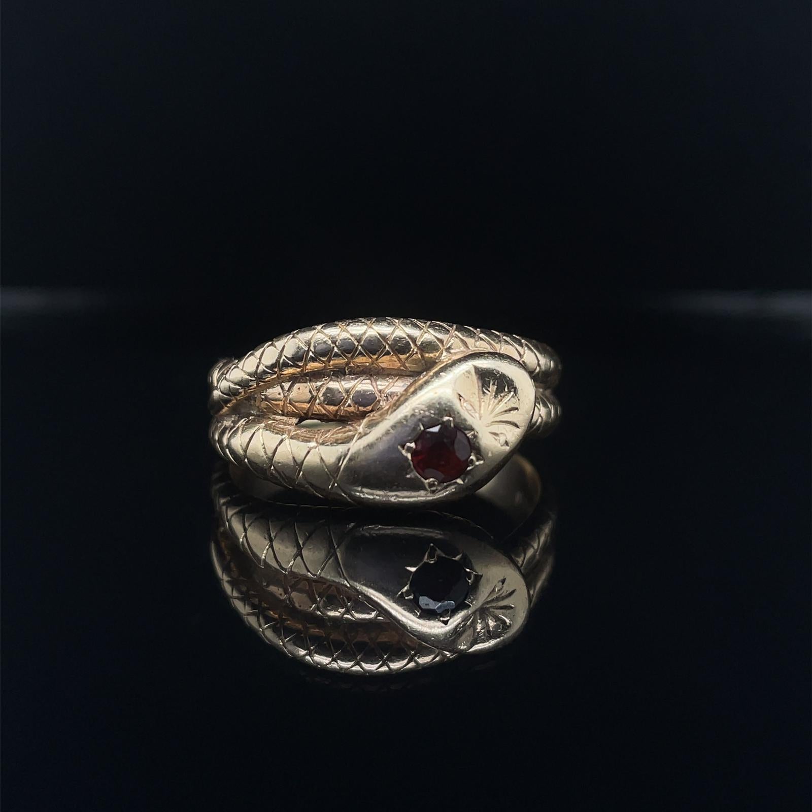 A vintage garnet 9 karat yellow gold snake ring, circa 1970.

This charming snake ring, coils twice around the finger of the wearer.

Excellently carved with the pattern of a realistically modelled snake throughout and star set with a round cut deep