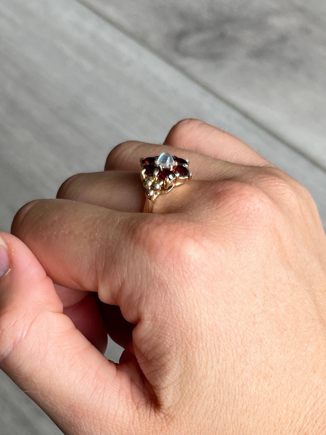This striking ring holds round cut garnets totalling approx 1.5ct and a moonstone at the centre. All the stones sit in 9carat gold claws. 

Ring Size: M or 6 1/4 
Cluster Diameter: 13mm
Height Off Finger: 6mm

Weight: 3.5g