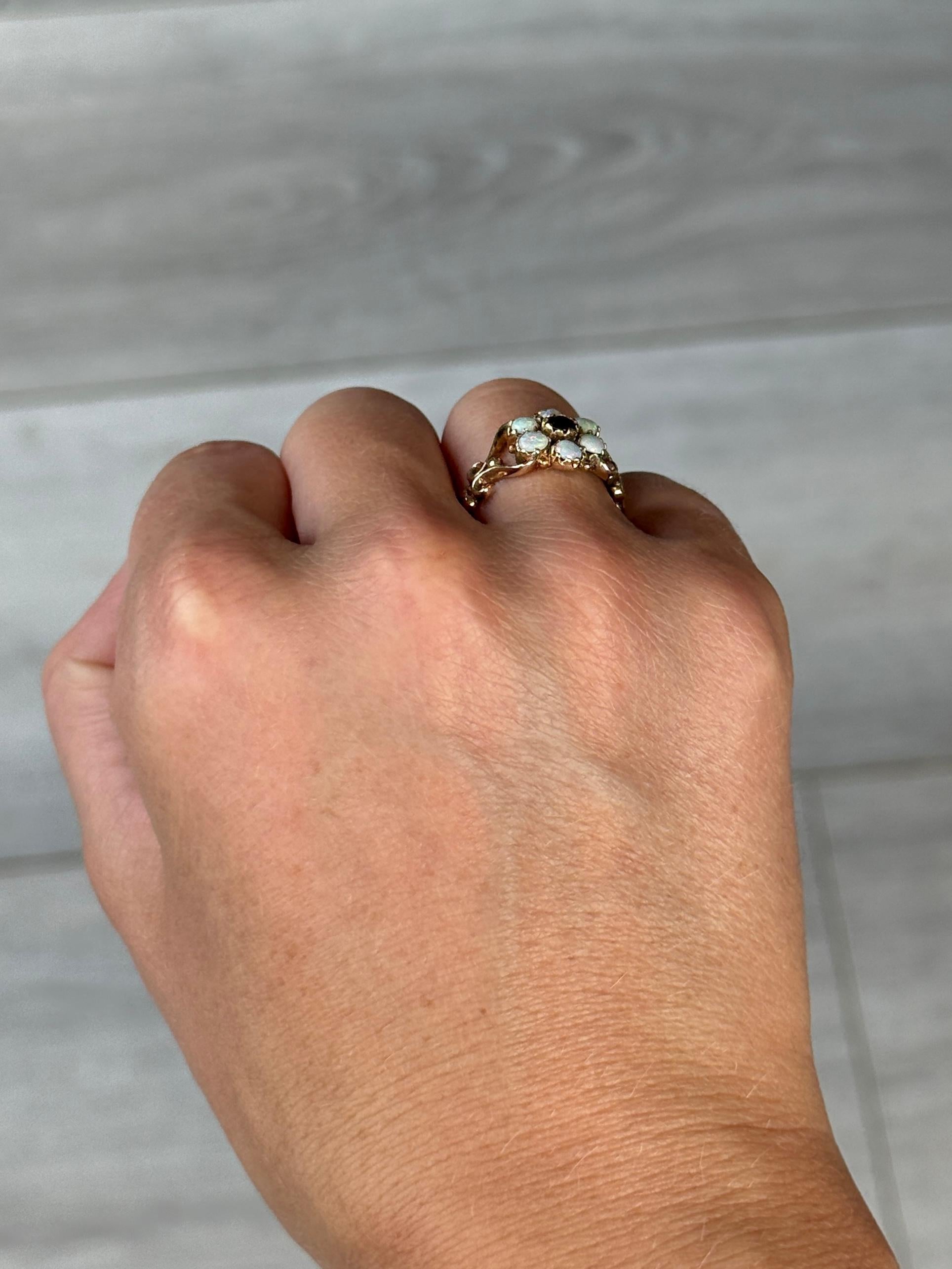 Dieser auffällige Ring enthält einen Granat von 15 pt. und Opale, die ihn umgeben. Alle Steine sitzen in Krallen aus 9 Karat Gold. Vollständig gestempelt London 1975.

Ring Größe: L 1/2 oder 6 
Cluster-Durchmesser: 11mm
Höhe ohne Finger: