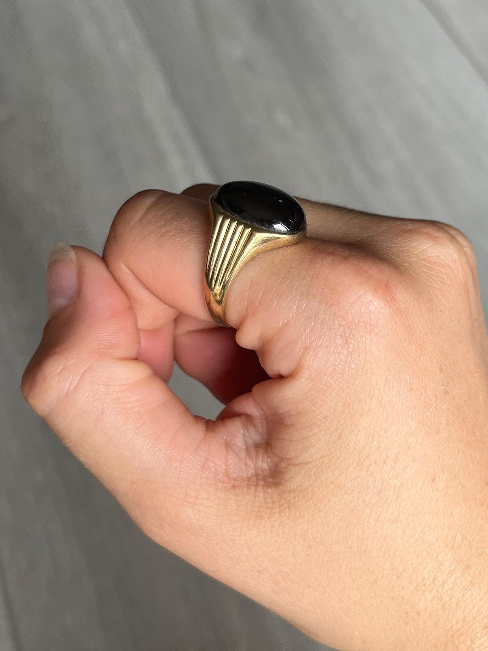 Auf einem wunderschönen, glänzenden Band aus 9 Karat Gelbgold sitzt ein ebenso glänzender Granat-Cabochon. Der Stein erstreckt sich fast über die gesamte Breite des Rings. 

Ringgröße: R oder 8 1/2 
Breite des Bandes an der breitesten Stelle: 18