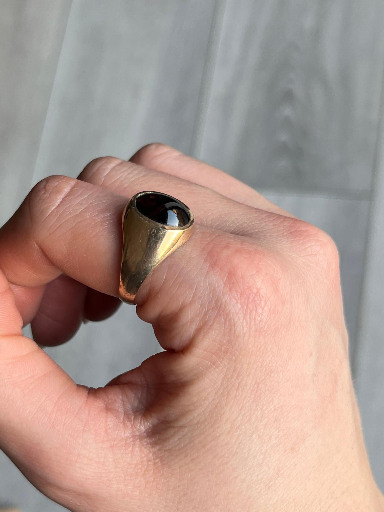 Sat proud upon a gorgeous glossy 9ct yellow gold band is an equally glossy garnet cabochon stone. The stone nearly spans the whole width of this ring. Made in London 1978, England.

Ring Size: U or 10
Band Width At Widest: 14mm

Weight: 3.4g