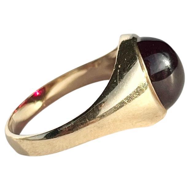 Sat proud upon a gorgeous glossy 9ct yellow gold band is an equally glossy garnet cabochon stone. The stone nearly spans the whole width of this ring. Made in London 1975, England.

Ring Size: O 1/2 or 7 1/2 
Stone Dimensions: 10x8mm

Weight: 3g