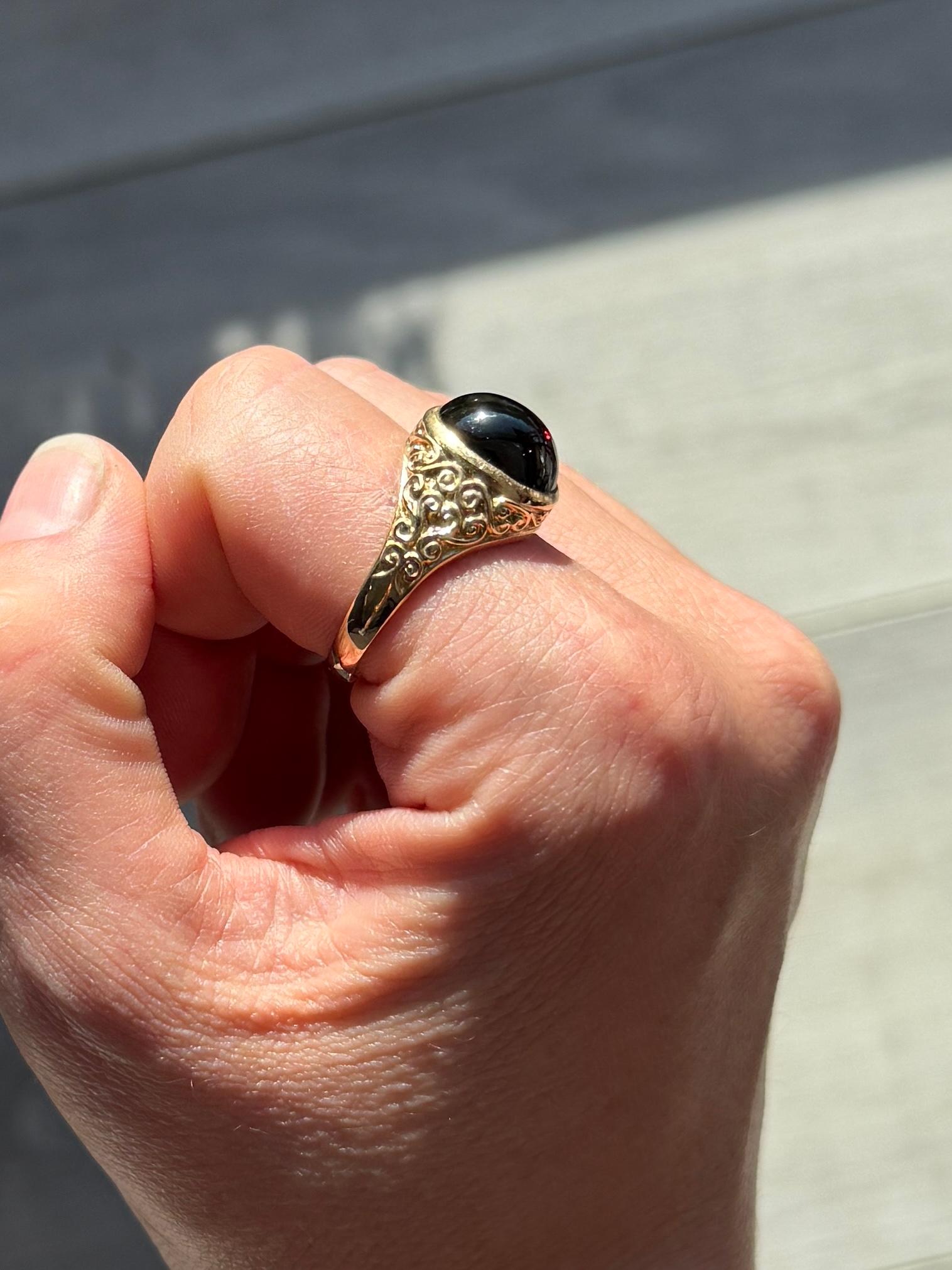 Sat proud upon a gorgeous glossy 9ct yellow gold band is an equally glossy garnet cabochon stone. The stone nearly spans the whole width of this ring. Made in London 1993, England.

Ring Size: T or 9 1/2 
Stone Dimensions: 12x10mm

Weight: 5.6g