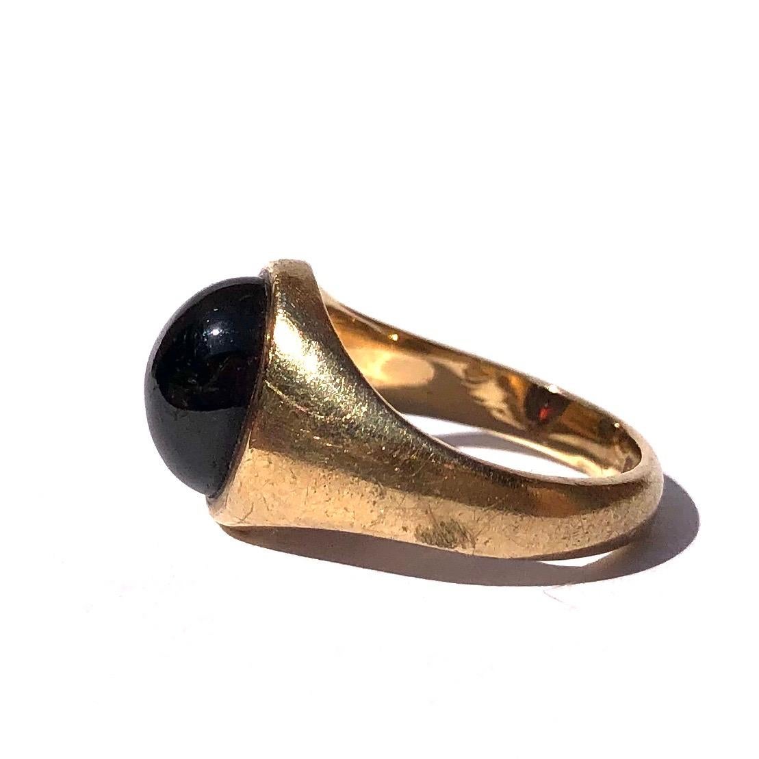 Sat proud upon a gorgeous glossy 9ct yellow gold band is an equally glossy garnet cabochon stone. The stone is slightly oval and nearly spans the whole width of this ring. Made in Birmingham, England.

Ring Size: G or 3 1/3 
Band Width At Widest: