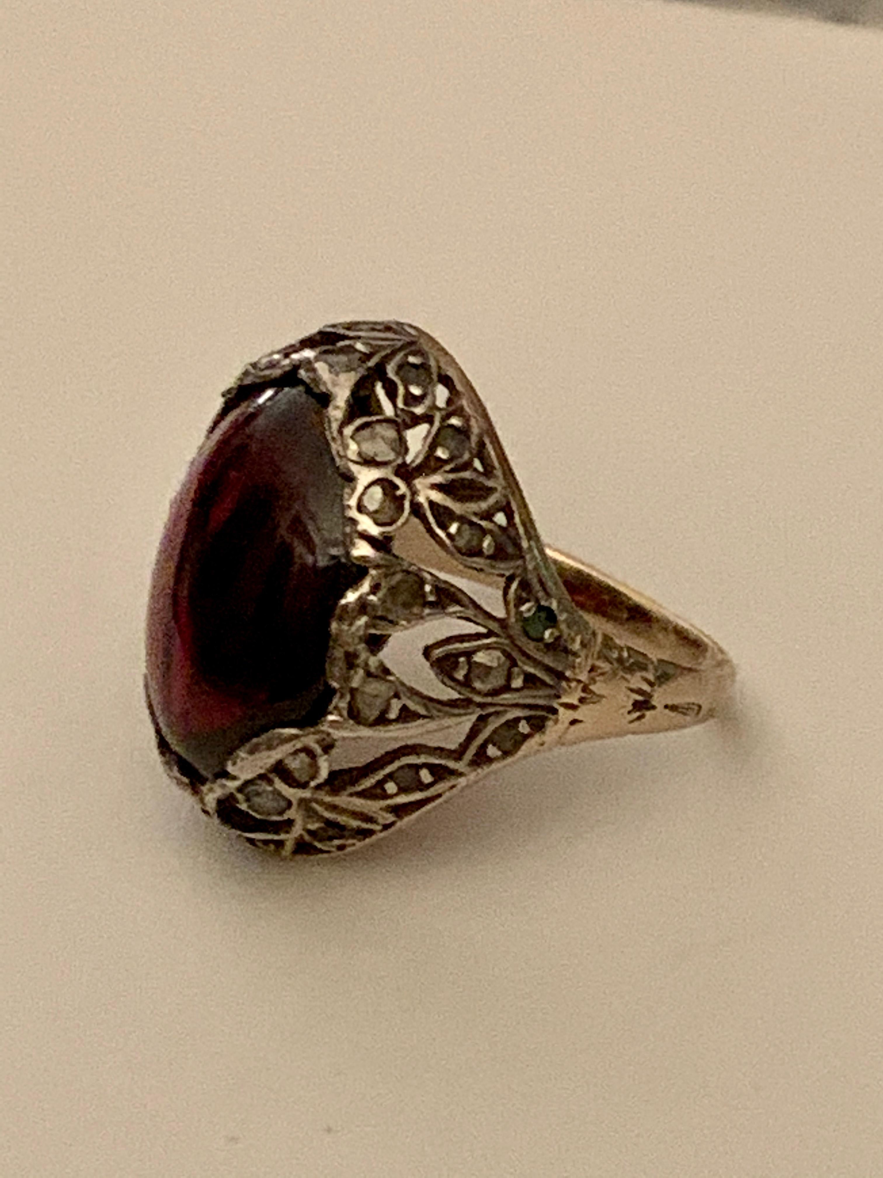 This vintage ring features a setting that's as beautiful, if not more beautiful, than the center stone itself!  The center stone, a Garnet cabochon, is surrounded by a beautiful 10 karat yellow Gold setting with a design which extends down each side