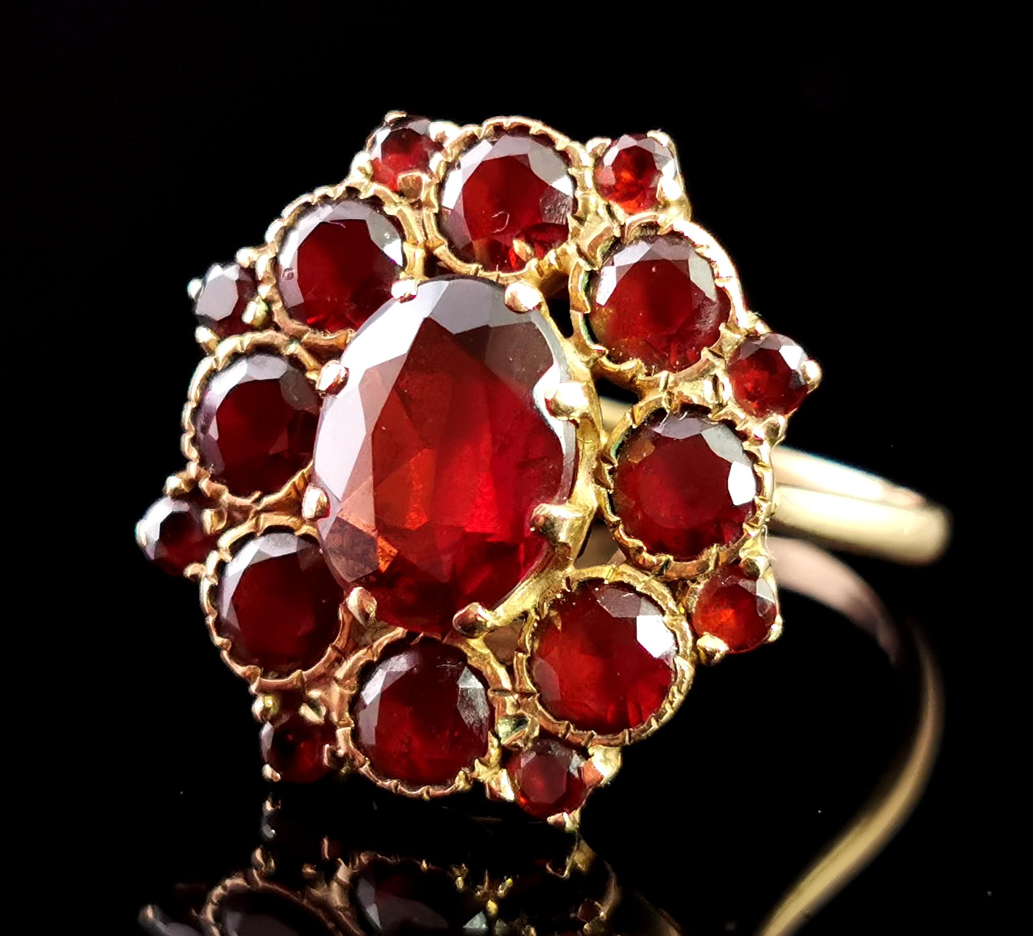 A gorgeous vintage garnet dress ring.

If you were looking for a cluster ring with oomph then this is your girl!

To the centre there is a large, faceted oval cut garnet, rich, warm red, approximately 1.98 carat weight, the centre garnet is further