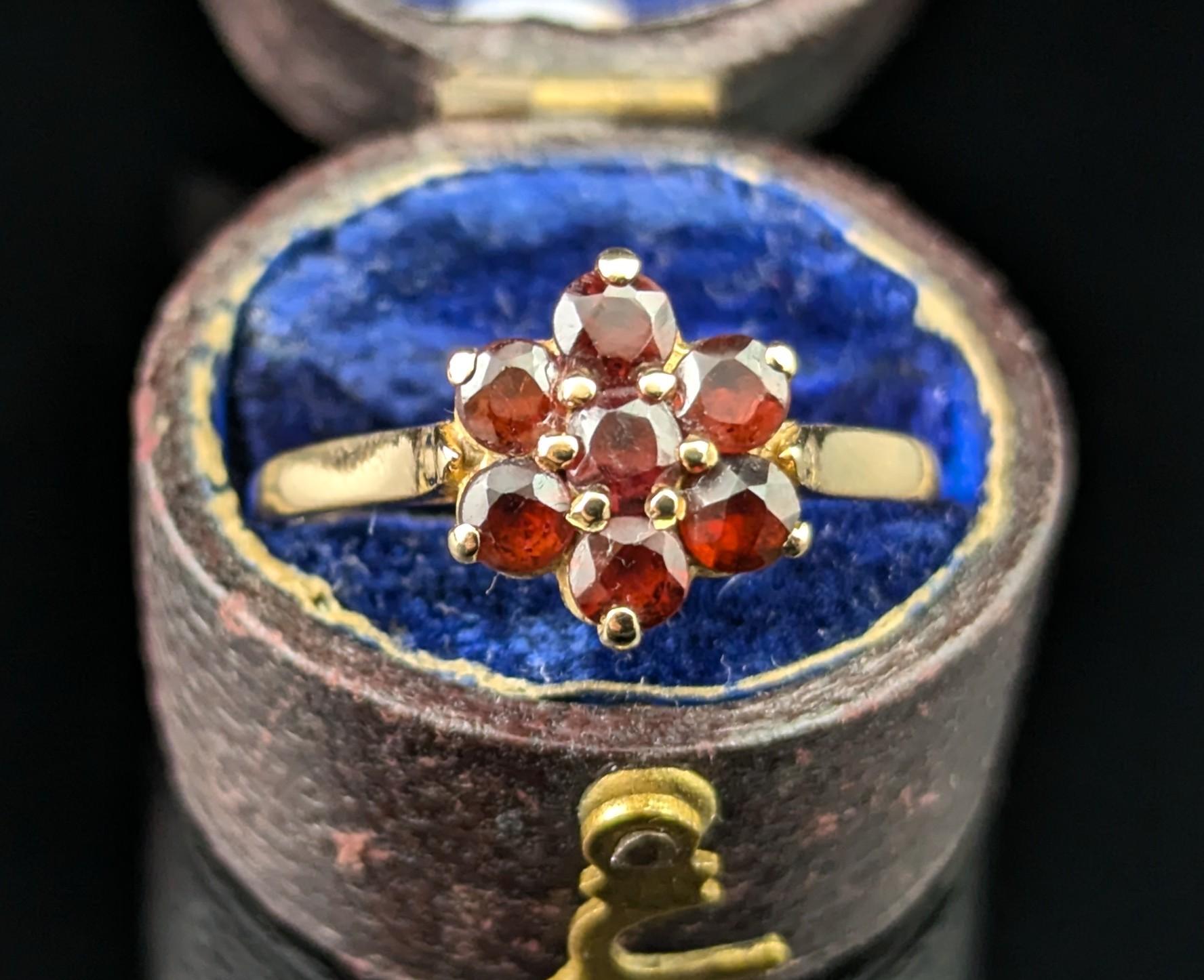 La plus belle bague vintage des années 1970 en forme de grappe de grenats.

Elle est réalisée en or jaune 9ct et ornée de grenats d'un rouge profond sertis dans un motif floral sur le visage.

La bague est délicate mais avec des tons audacieux. Elle