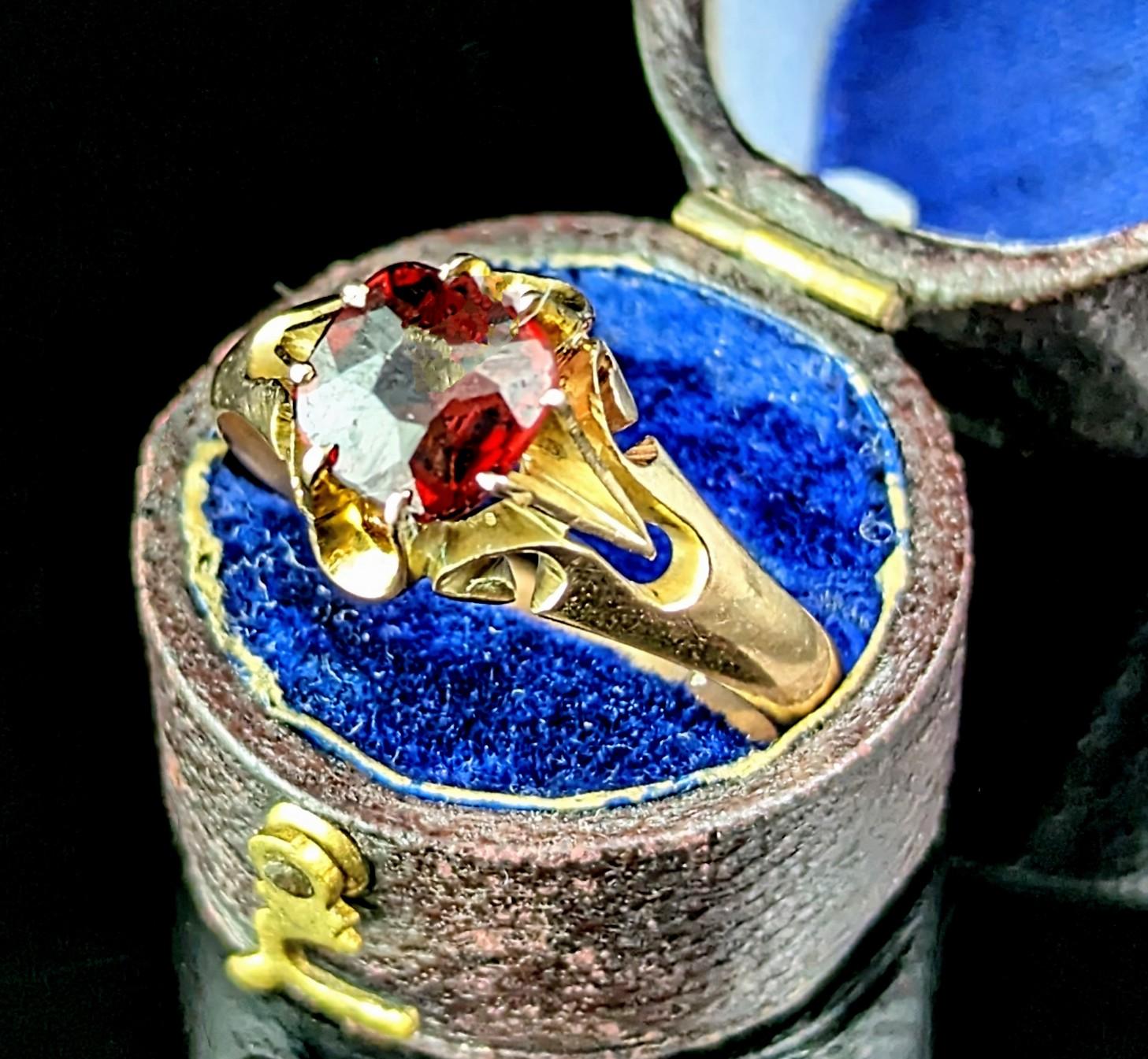 An interesting and handsome vintage Garnet solitaire ring.

It has a rich yellow gold mount with a single prong set cushion cut Garnet.

The ring has a decorative and elaborate face with short bifurcated shoulders and a smooth band.

The ring mount