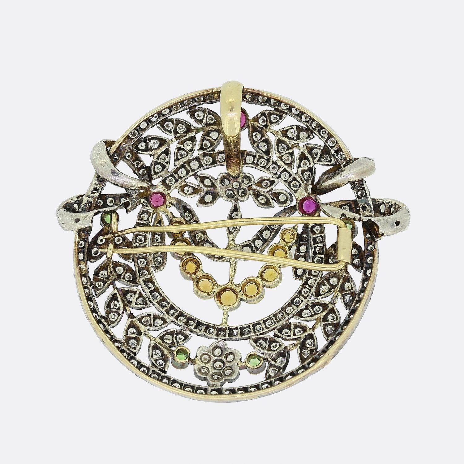 Voici un joli pendentif/broche vintage serti de pierres précieuses. Le pendentif est serti d'un ensemble de diamants ronds de taille brillant, de péridots, de rubis et de citrines dans un cadre floral en argent. Le dos comporte une boucle de