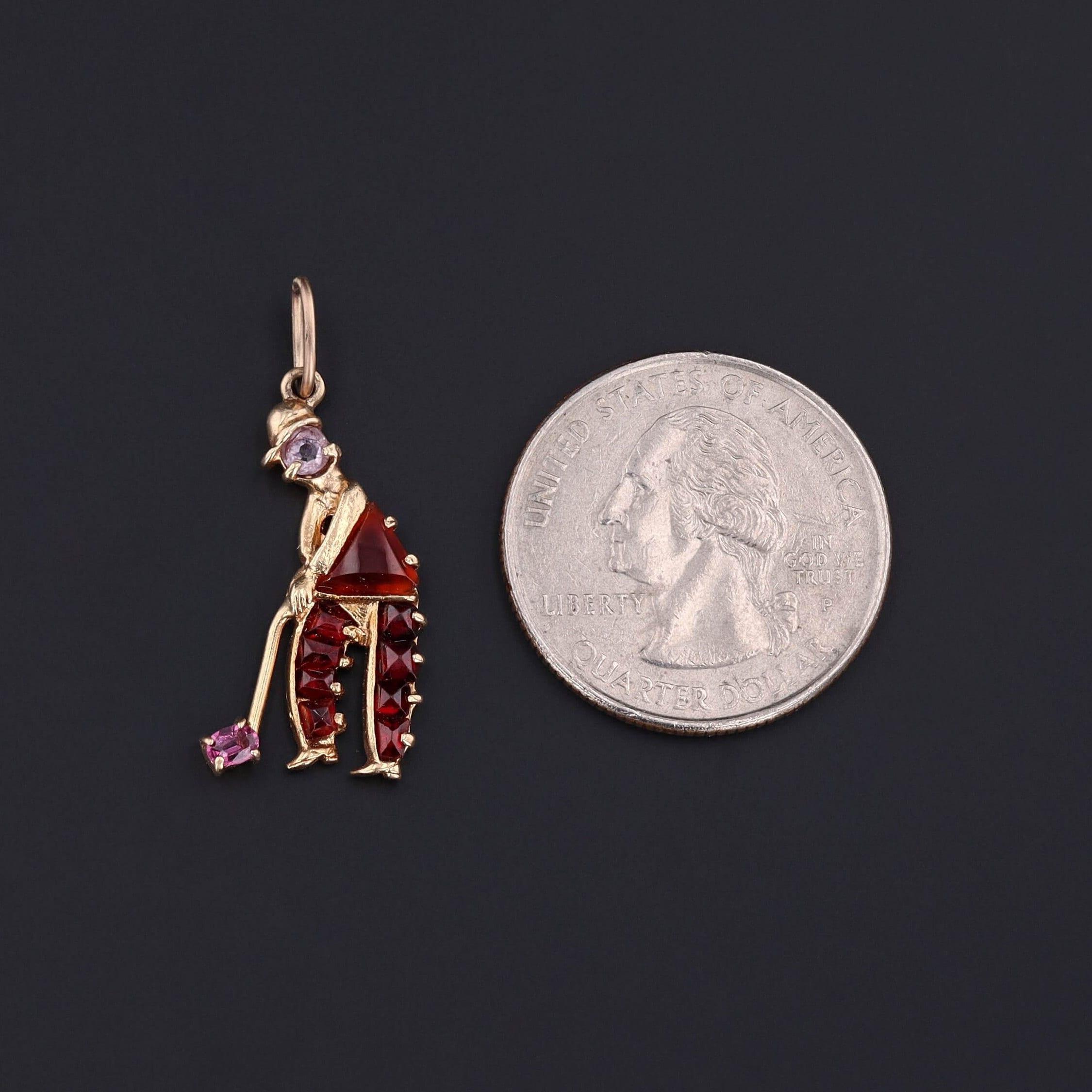 Questo ciondolo vintage (1940-1955 circa) presenta un giocatore di golf di quarzo, granato, corniola e ametista incastonati in oro 14k.

Il pezzo misura 1,3 pollici dalla parte superiore dell'anello di salto alla parte inferiore per 0,6 pollici di