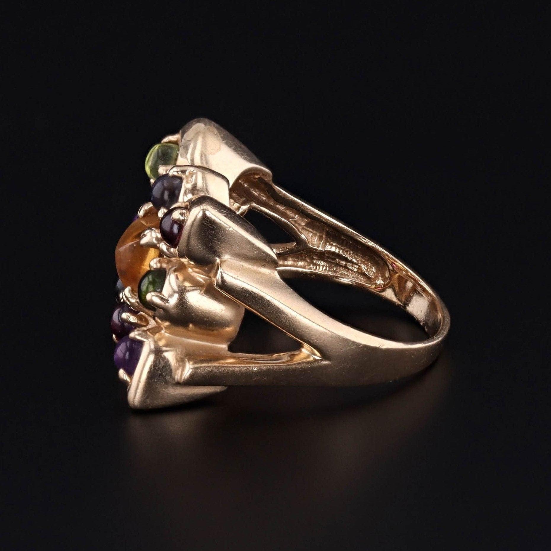 This vintage ring (circa 1960-1970) features a grid of assorted gemstone cabochons set in 14k gold.

The gemstones include citrine, green tourmaline, blue tourmaline, garnet, amethyst, and chalcedony.

The face of the ring measures 0.7 inches by 0.7