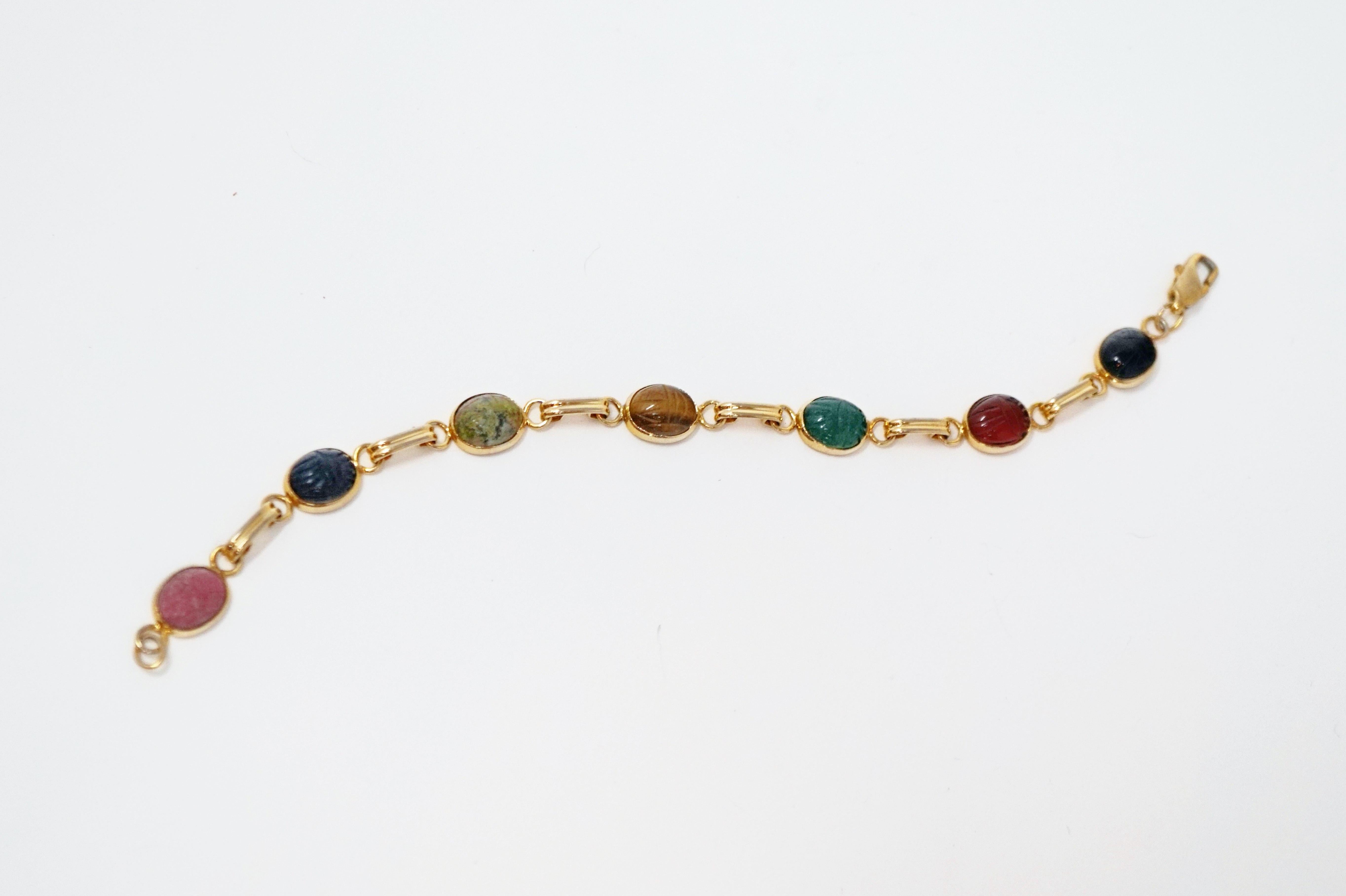 Vintage gold tone scarab beetle bracelet crafted with carved gemstones like Onyx, Agate, Lapis Lazuli and Tiger's Eye between gold tone links with a clasp closure.

The scarab beetle has been a symbolic motif in Egyptian jewelry for thousands of