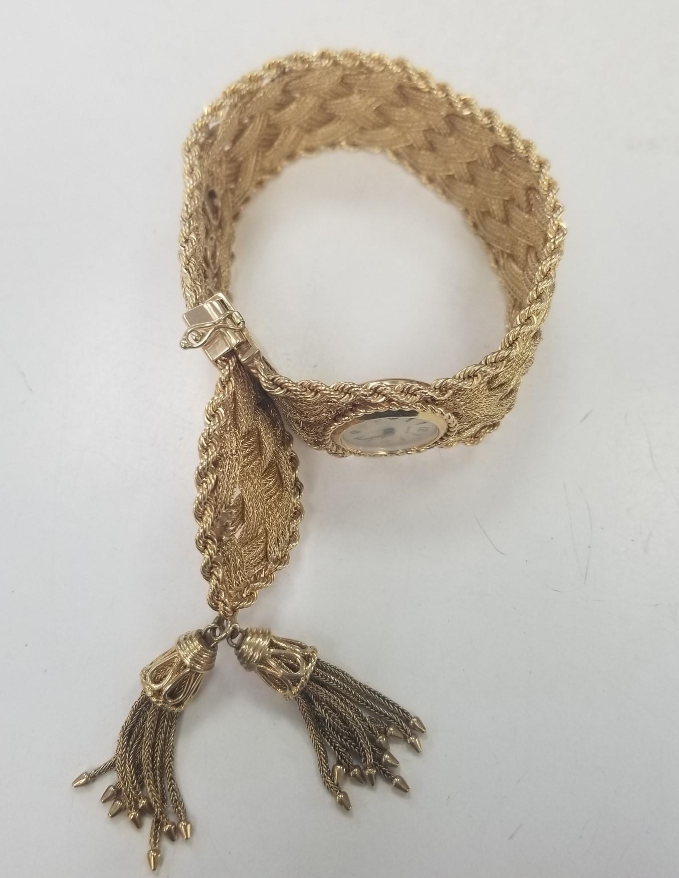 Vintage Geneve 14 Karat Yellow Gold Woven and Rope Bracelet Watch with Tassels .  The watch has 4 adjustments 6 inches -7/5 inches with a safety pin and clasp.  The Watch has a brand new movement.  The width is 26mm and weighs 73 grams. 
