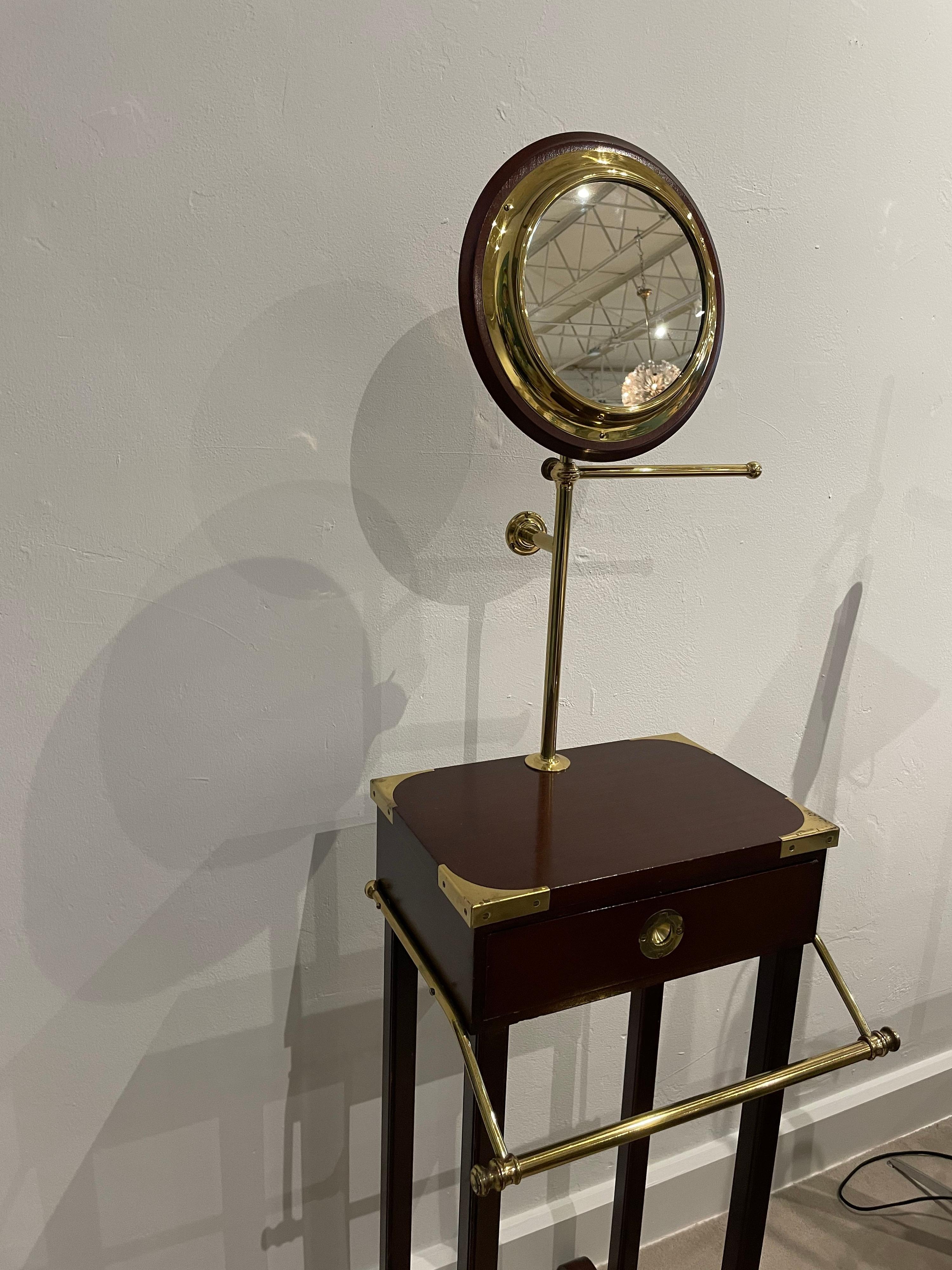 Sourced from the Oyster Bay, NY estate of famed fashion designer, Geoffrey Beene, this campaign style shaving stand with articulating mirror in the shape of a porthole. Single drawer and brass rack for shaving towel, this stand can be fixed to the