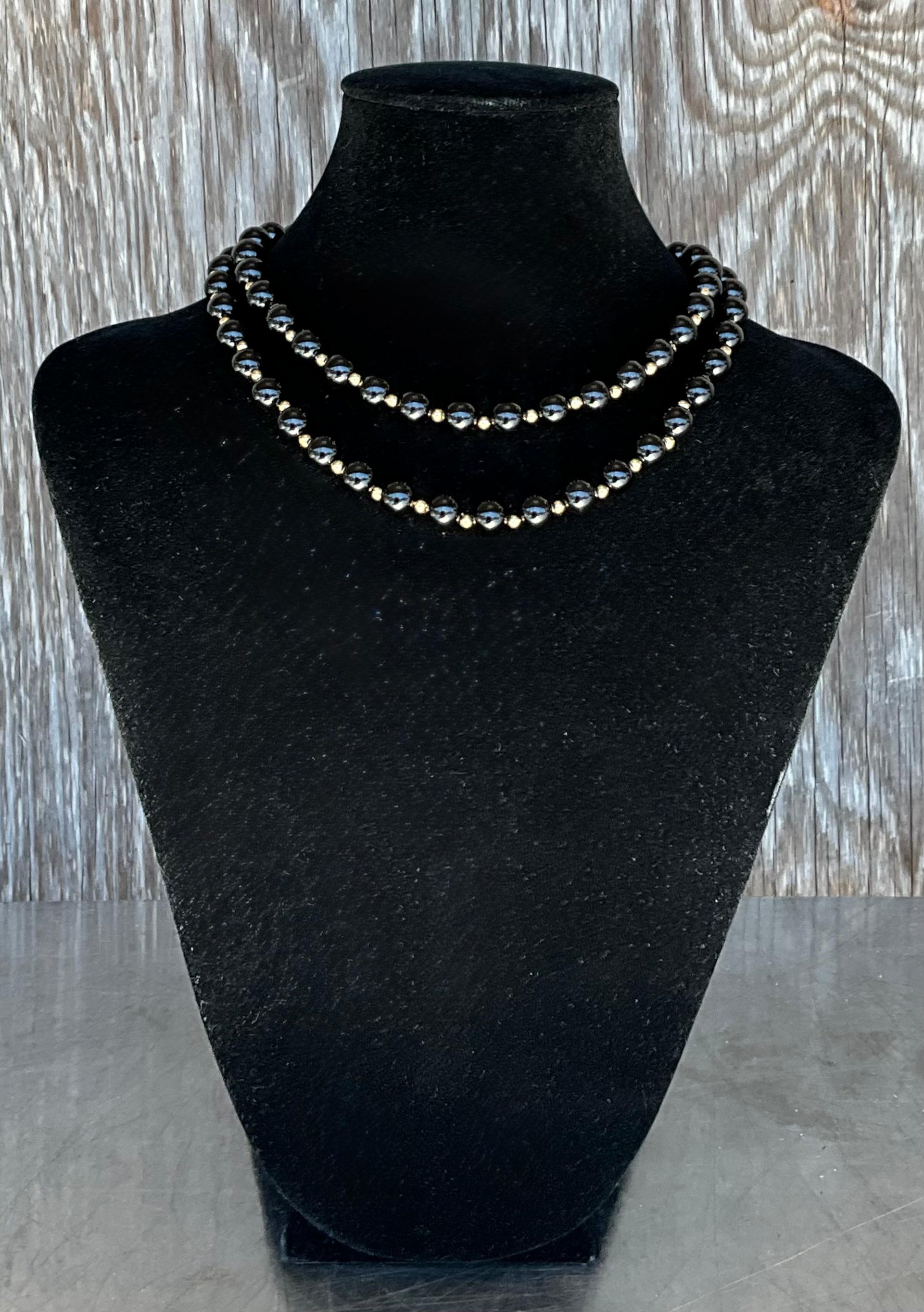 The Vintage Genuine Black Onyx Necklace with 14k Gold Embellishments is an elegant, timeless piece that exudes sophistication and luxury. The deep black onyx paired with the warm gold accents creates a striking contrast, making it a versatile