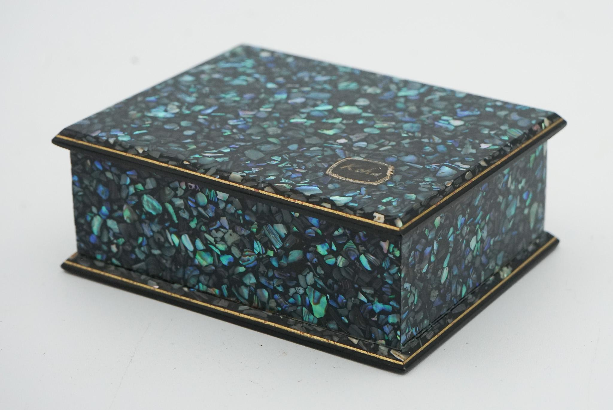 
Cette boîte à bijoux vintage en paua shell abalone de Nouvelle-Zélande présente un extérieur poli en paua shell vibrant, avec des couleurs irisées allant des bleus et des verts profonds. 

L'intérieur est doublé d'un tissu doux pour protéger les