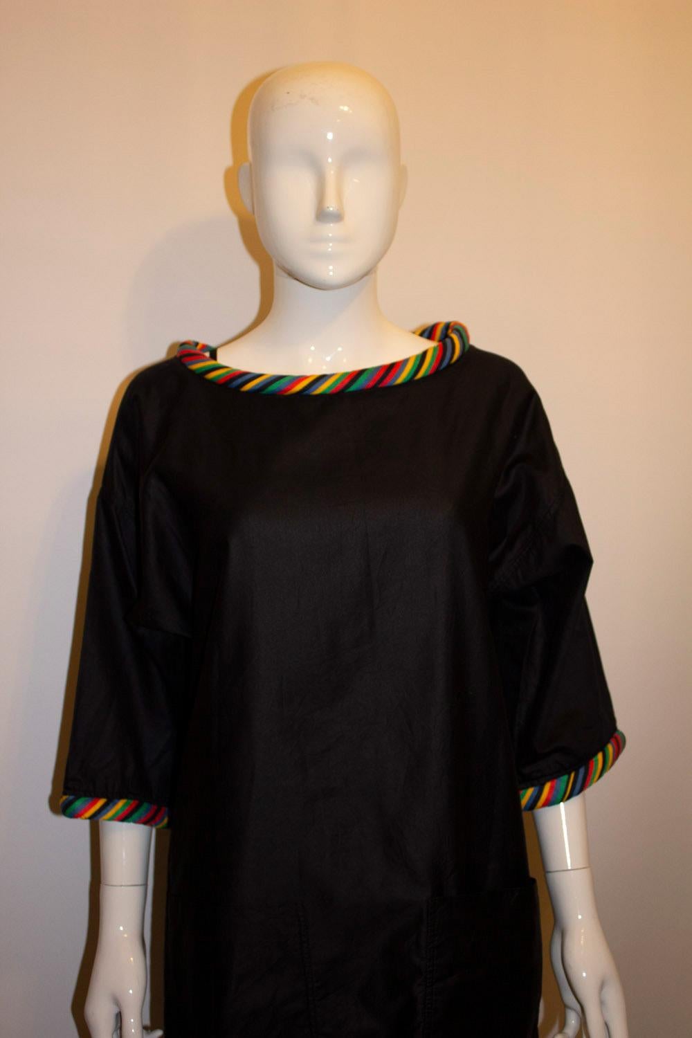 A chic and easy to wear dress by Geoffrey Beane. The dress is in a very dark blue /black satinised cotton with multicolour woven trim on the neckline and cuffs. It has two pockets and a5'' slit on either side.  US size 8, measurements; Bust up to