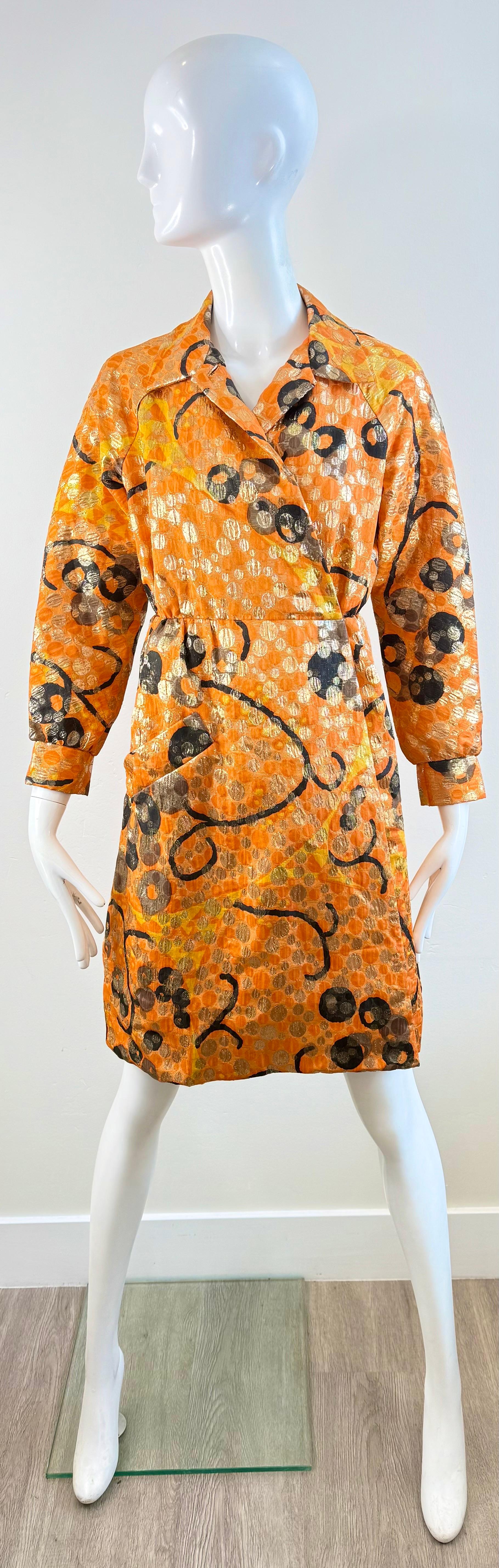 This vintage Geoffrey Beene coat dress from the 1960s is a rare, versatile piece that reflects the designer’s innovative vision. Crafted in a bold orange metallic brocade with abstract circular and swirling motifs, it is designed as a wrap style