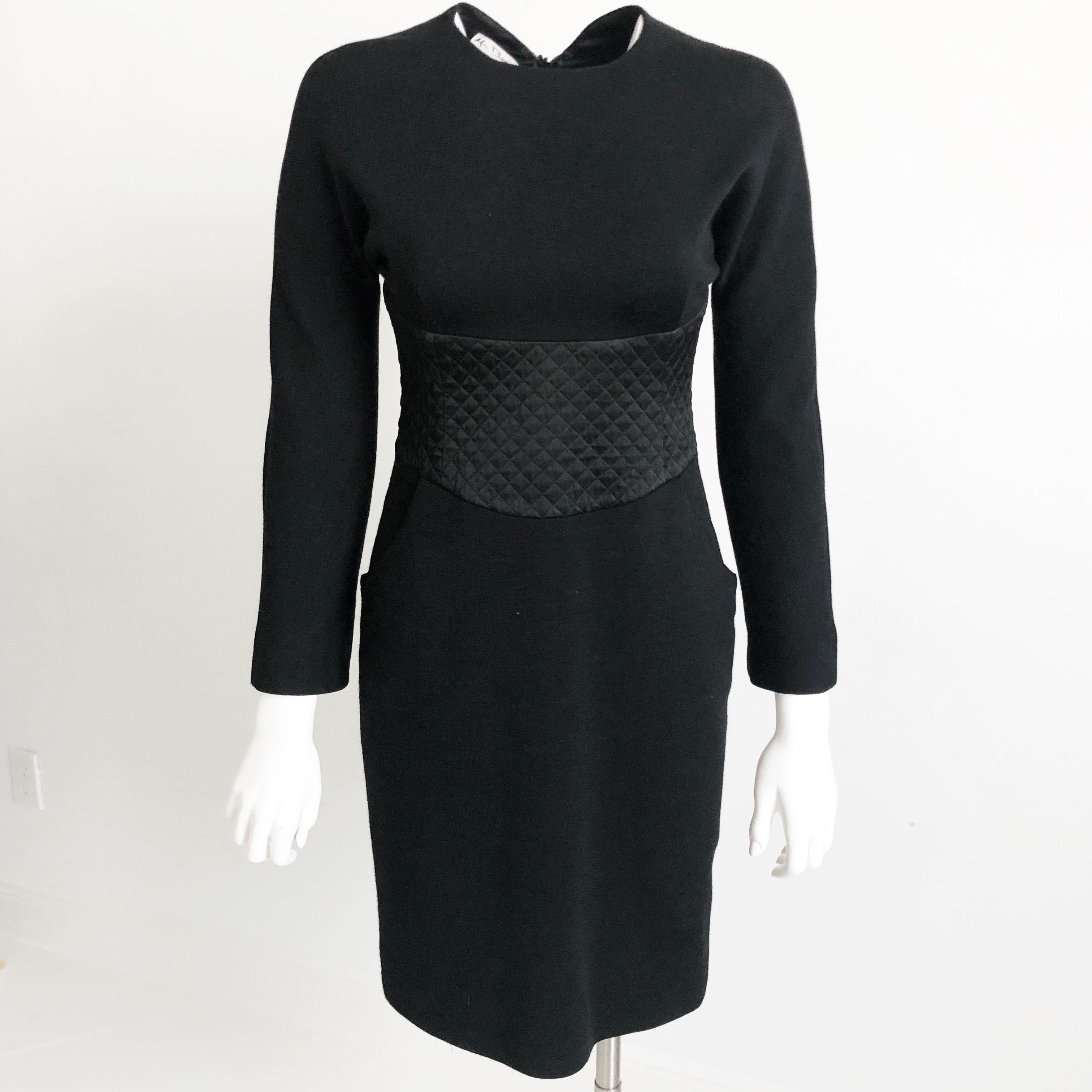 Authentic, preowned, vintage Geoffrey Beene little black dress, size 6, likely made in the 90s. Made from wool & silk satin, fully lined in silk.  Features Raglan sleeves, a silk satin quilted panel on front & back and hip pockets; fastens with rear