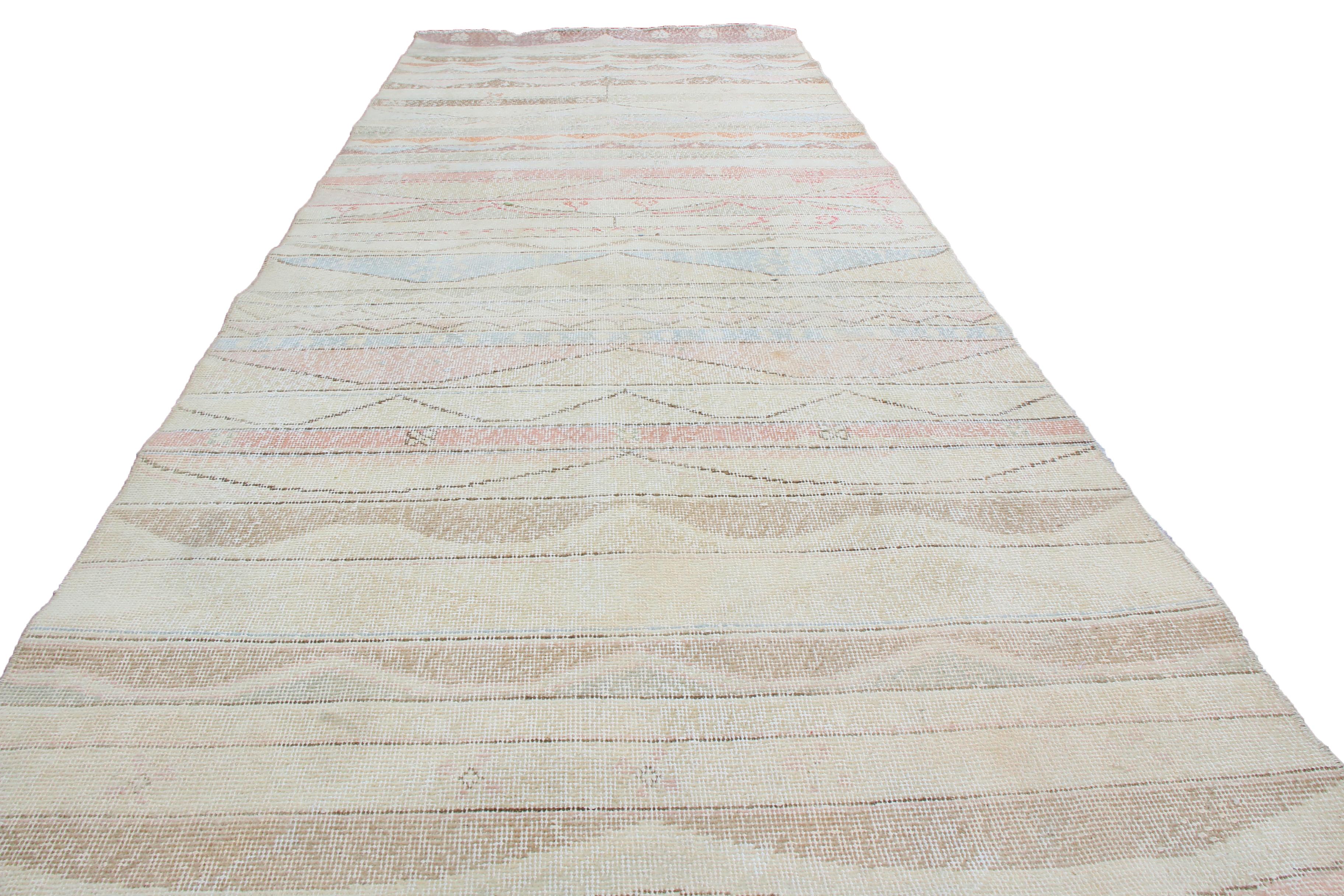 Originating from Turkey in 1940 featuring hand knotted, high quality wool and this vintage geometric rug hosts remarkably subtle floral imagery in the rows defining its field design, complemented by a uniquely fine guard border enveloping pastel