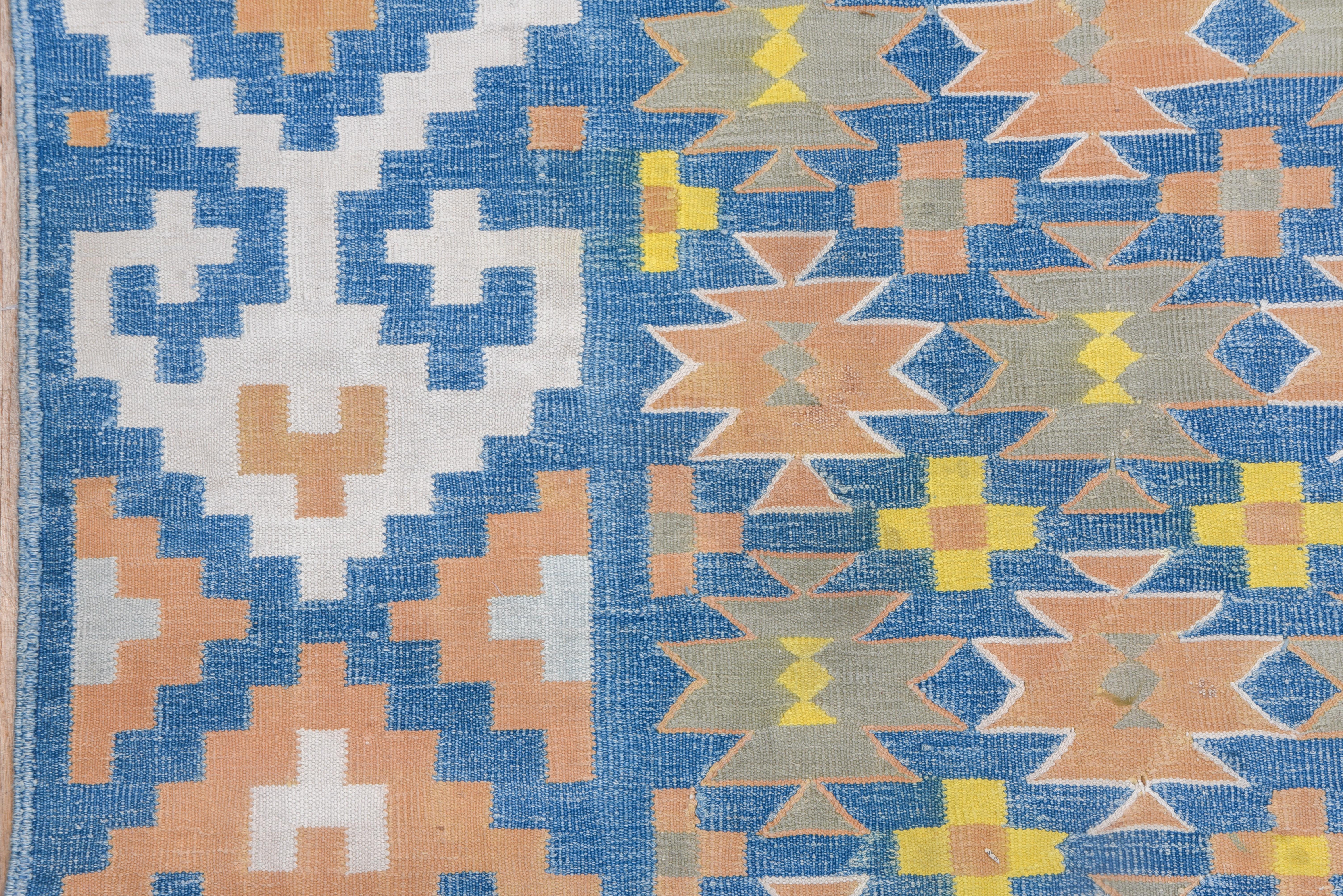 The luminous light/medium blue ground hosts rows and columns of small ashiks and small crosses, detailed in goldenrod, ecru, khaki and buff. Matching blue strip style order with off white and buff hexagons with arrowhead finials. Tapestry weave, all