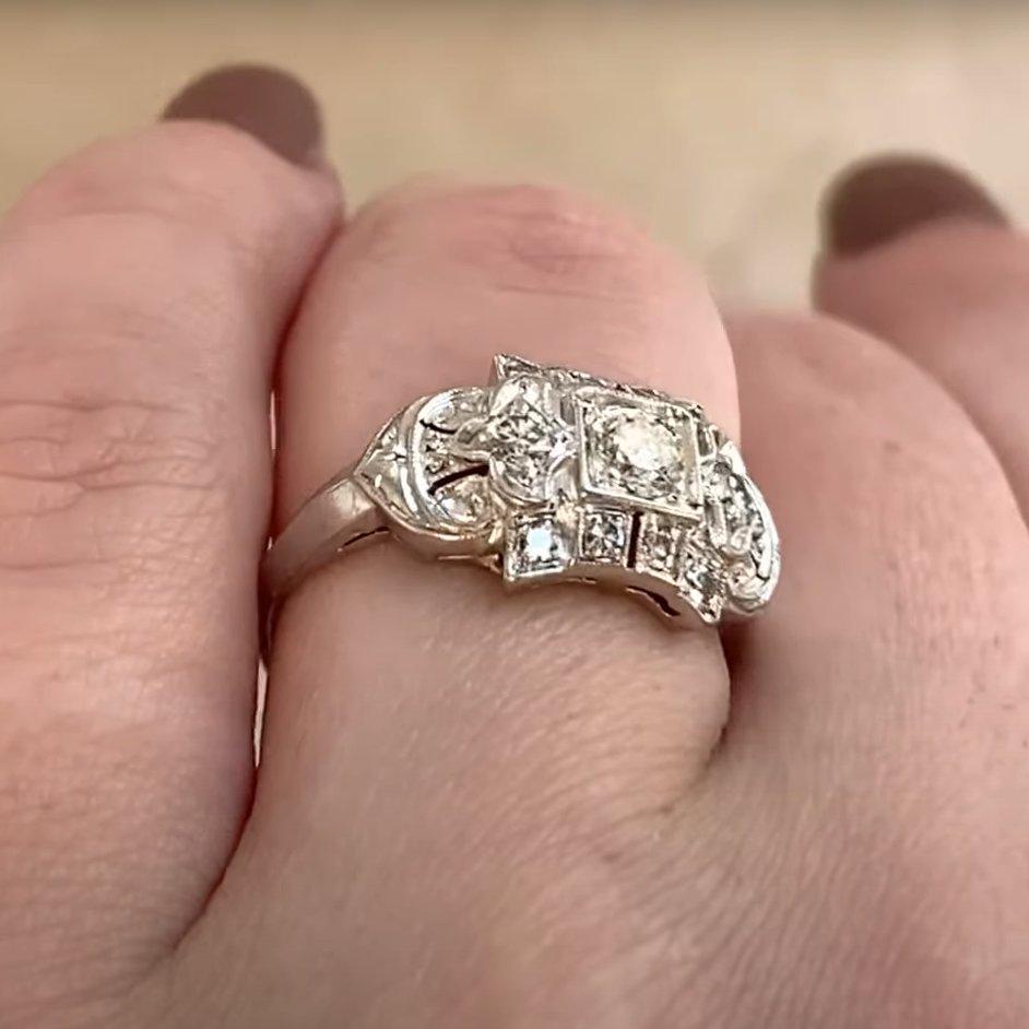 Este anillo vintage, hecho a mano en platino hacia 1950, centra un brillante diamante redondo de talla brillante que pesa aproximadamente 0,10 quilates. La piedra central es de color I con claridad VS1, y ofrece un aspecto brillante y limpio con un
