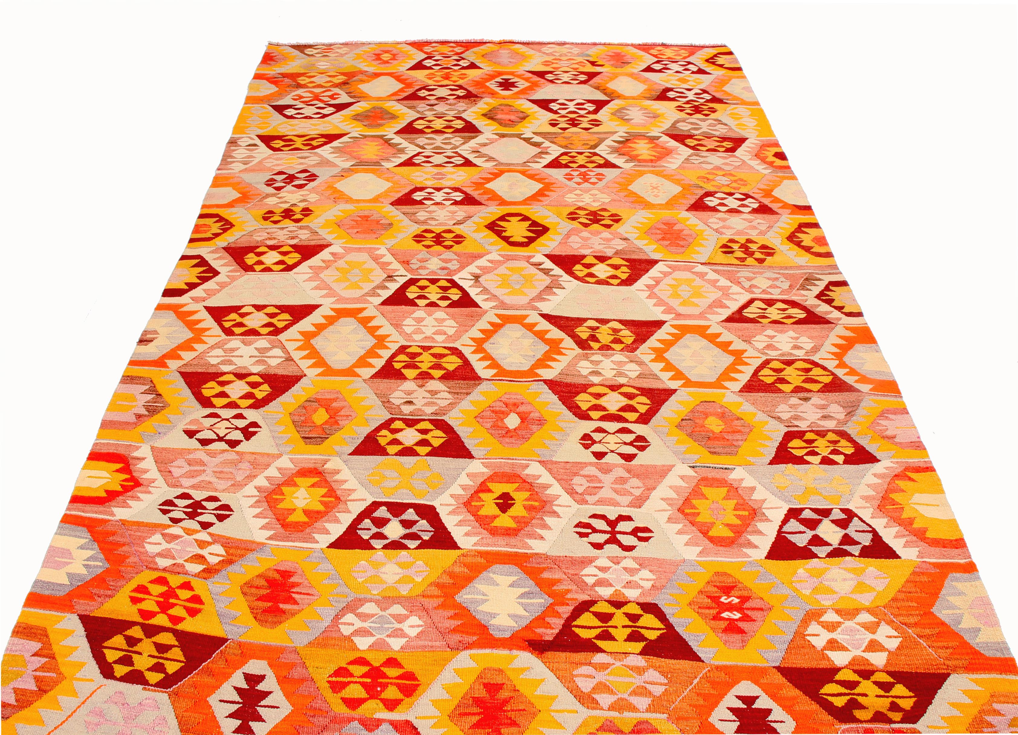 Handwoven with high-quality wool originating from Turkey between 1940-1950, this vintage geometric Kilim rug enjoys a tastefully abrashed pallet of muted-but-lively blue, orange, golden-yellow, white, and multi-tonal pink colorways highlighting the