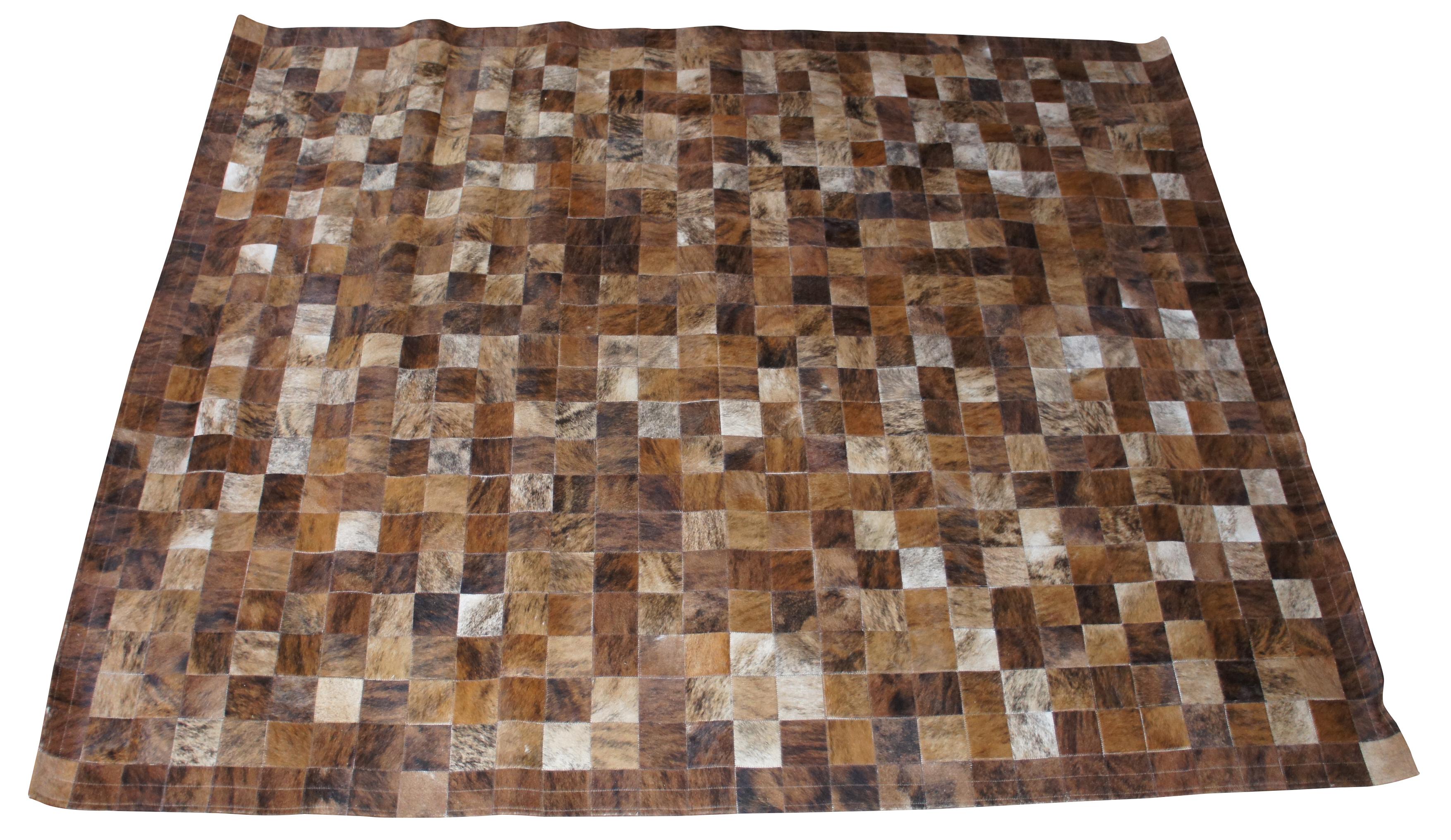 Vintage cow hide patchwork area rug featuring geometric squares of brown, white and black. Measures: 8' x 10'.
 