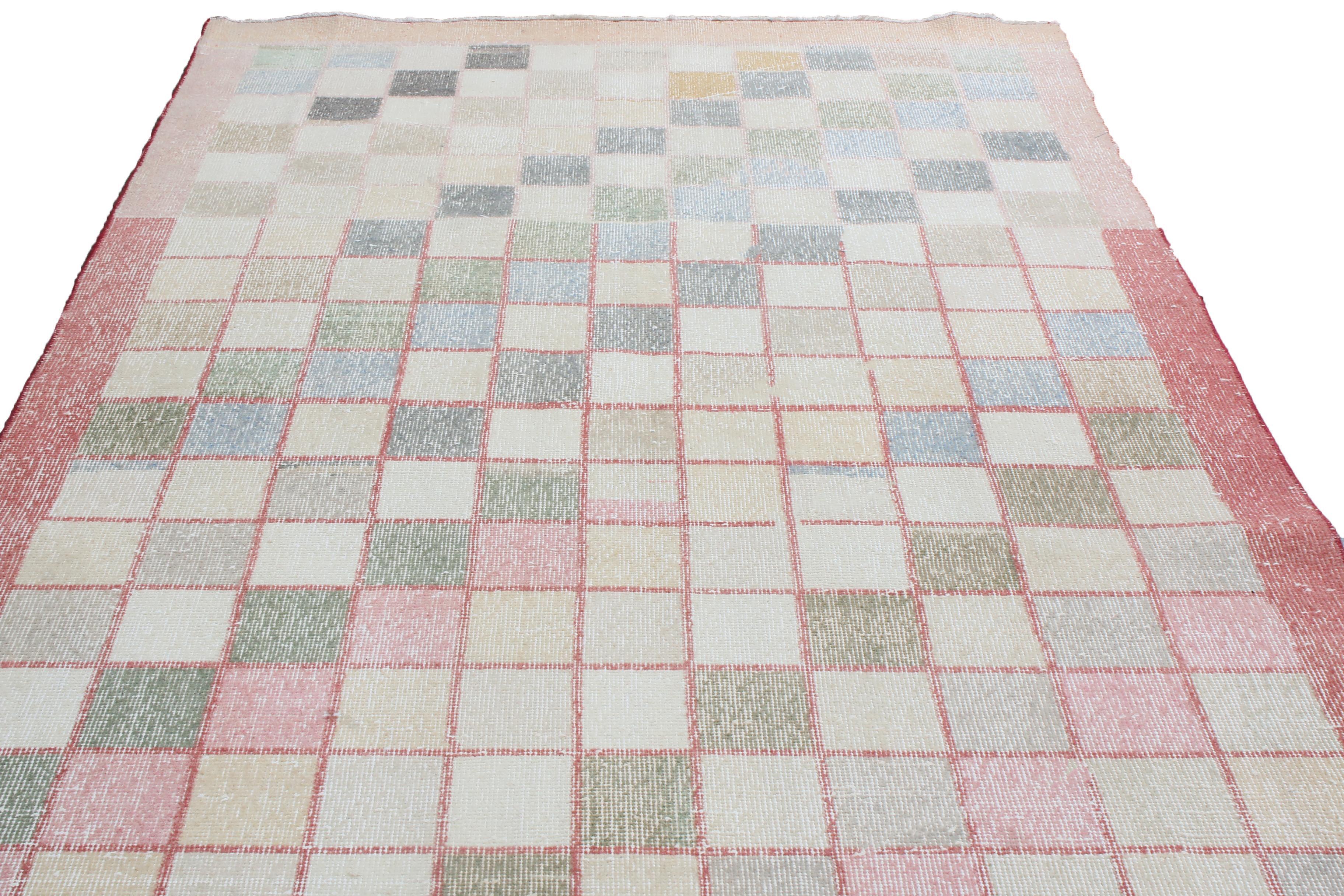 Hand knotted in high-quality wool originating from Turkey in 1951, this vintage geometric rug enjoys an uncommon pairing of pastel pink and green colorways completing a bold but forgiving display in any area. Featuring low pile height, the unique