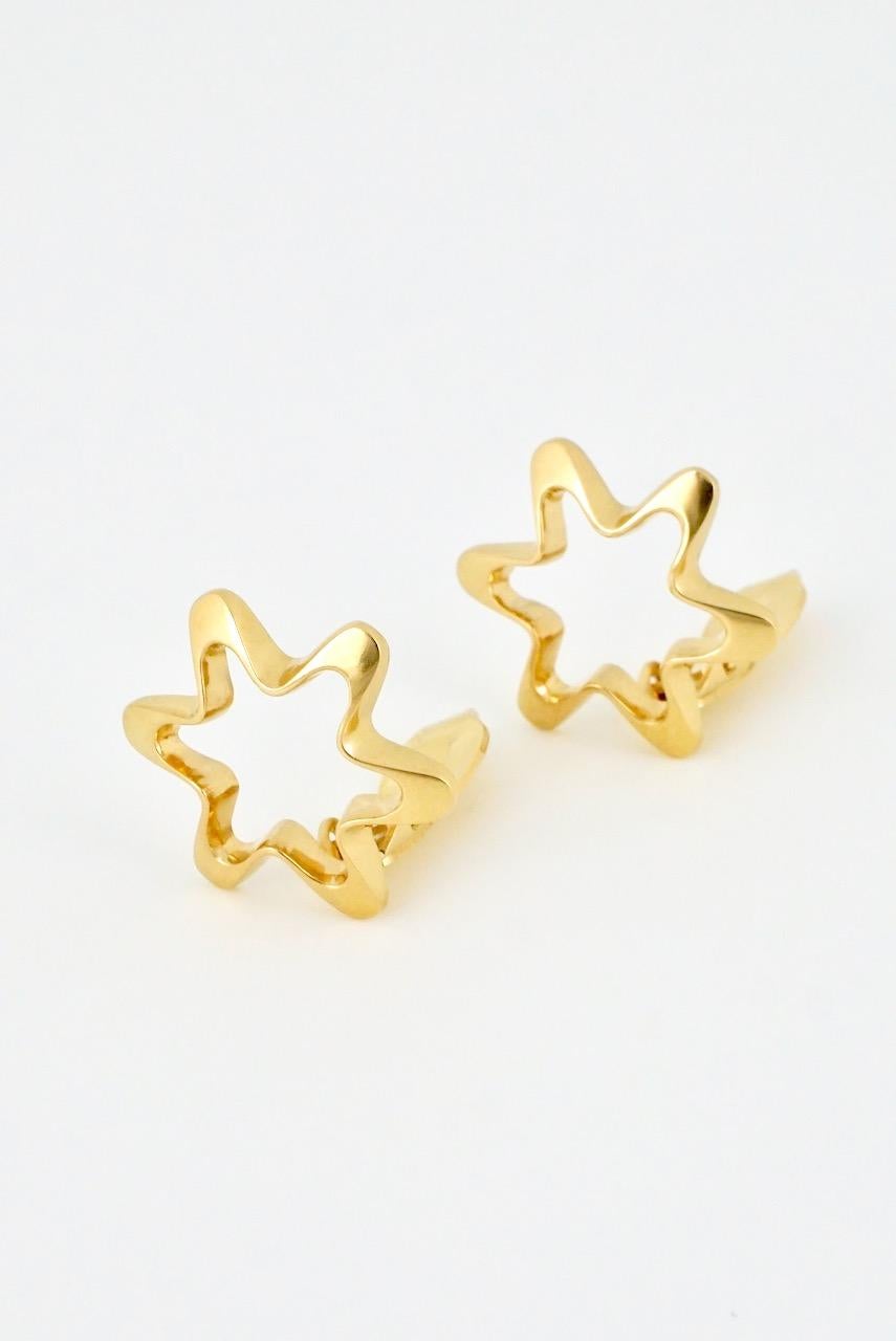 A vintage pair of 18k yellow gold clip earrings with each earring consisting of a rounded star motif with an open centre and clip back fitting - marked with post 1945 marks for Georg Jensen of Copenhagen and design number 1139 by Henning Koppel -