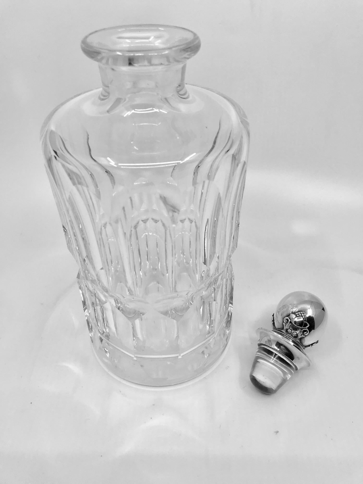This is a vintage crystal decanter with sterling silver Georg Jensen stopper in the Acorn pattern, design #384 by Johan Rohde.

Measures: 9 5/8? in total height with stopper, the bottle alone is 8? in height and has a diameter of 3 7/8? (24.5cm,
