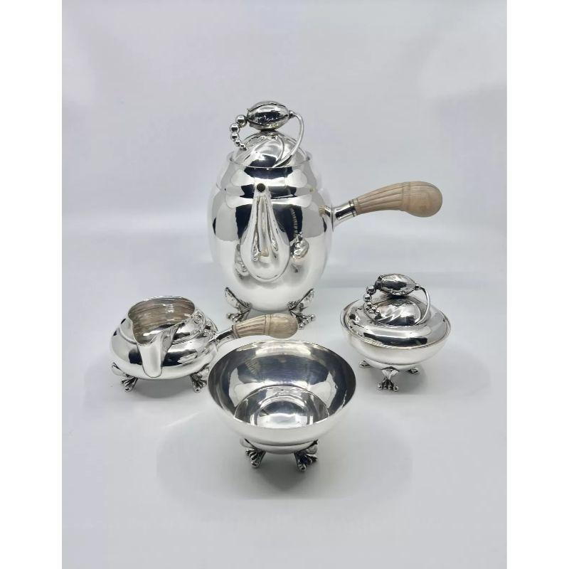A vintage Georg Jensen Blossom sterling silver tea and coffee service with ivory handles, design #2 by Georg Jensen from 1905. A rare set that includes the warmer and stand for the teapot.
This set includes – Hot water kettle on stand with burner
