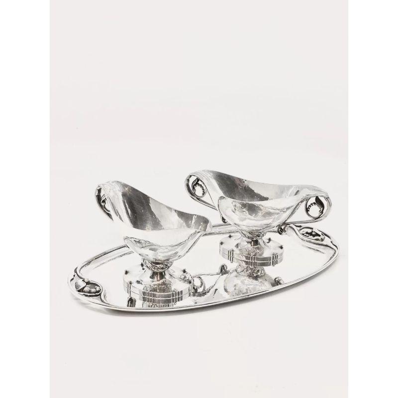 This is a sterling silver Georg Jensen hostess set, including sugar bowl, creamer and tray, design #71A by Georg Jensen from circa 1915. The handles are decorated with handmade pea pods, the stems are decorated with hand-chased leaves, all surfaces