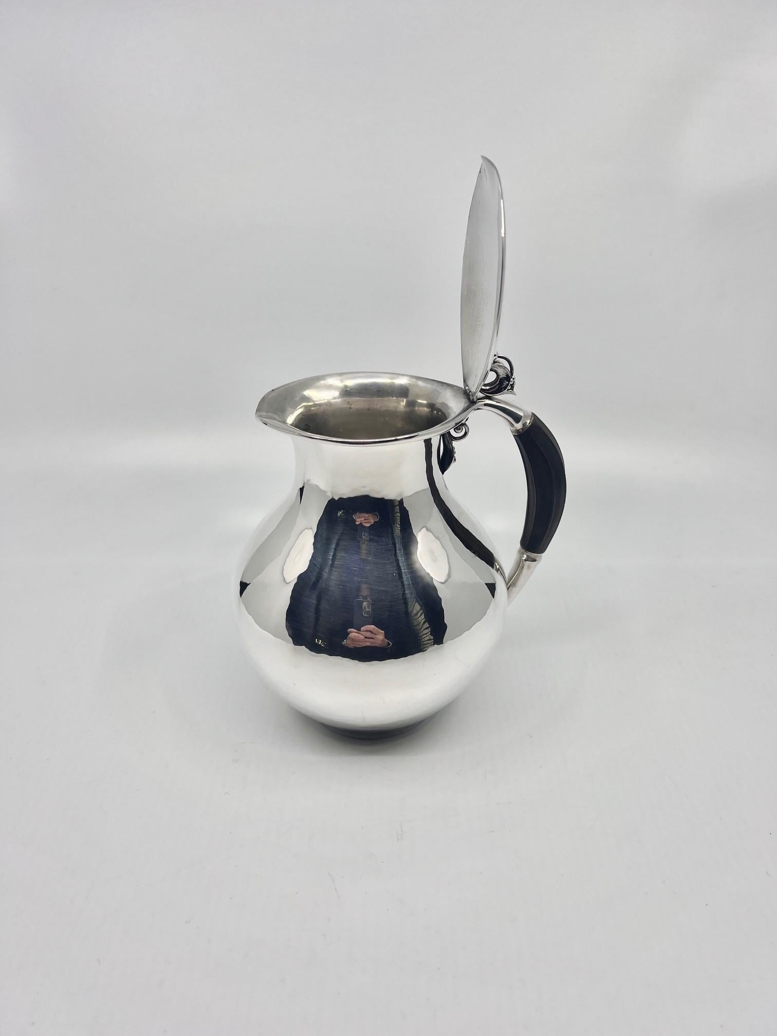 A sterling silver Georg Jensen pitcher with hinged lid and ebony handle, design #385C by Jorgen Jensen, one of Georg Jensen’s sons. Jorgen Jensen designed for Jensen from 1936-1962, he is best known for his Art Deco designs. This pitcher is one of