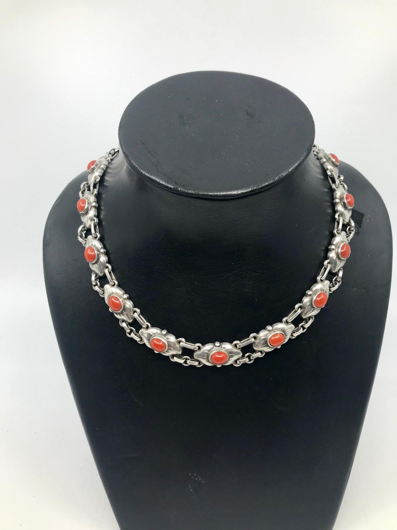 Georg Jensen silver necklace with 15 cabochon set coral stonesand a single large silver bead on the lock, design #22 by Georg Jensen.
Measures 17